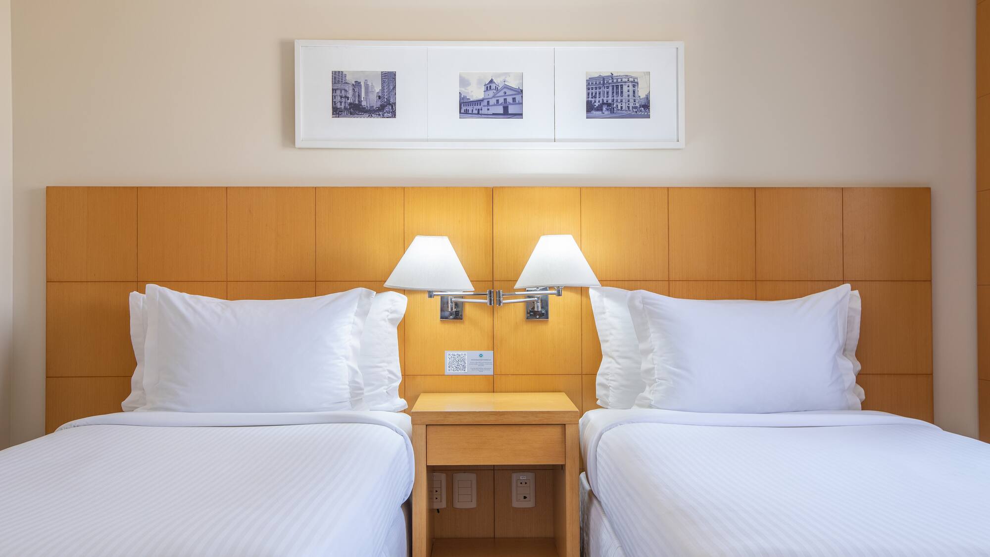 two beds with white sheets and lamps in a hotel room
