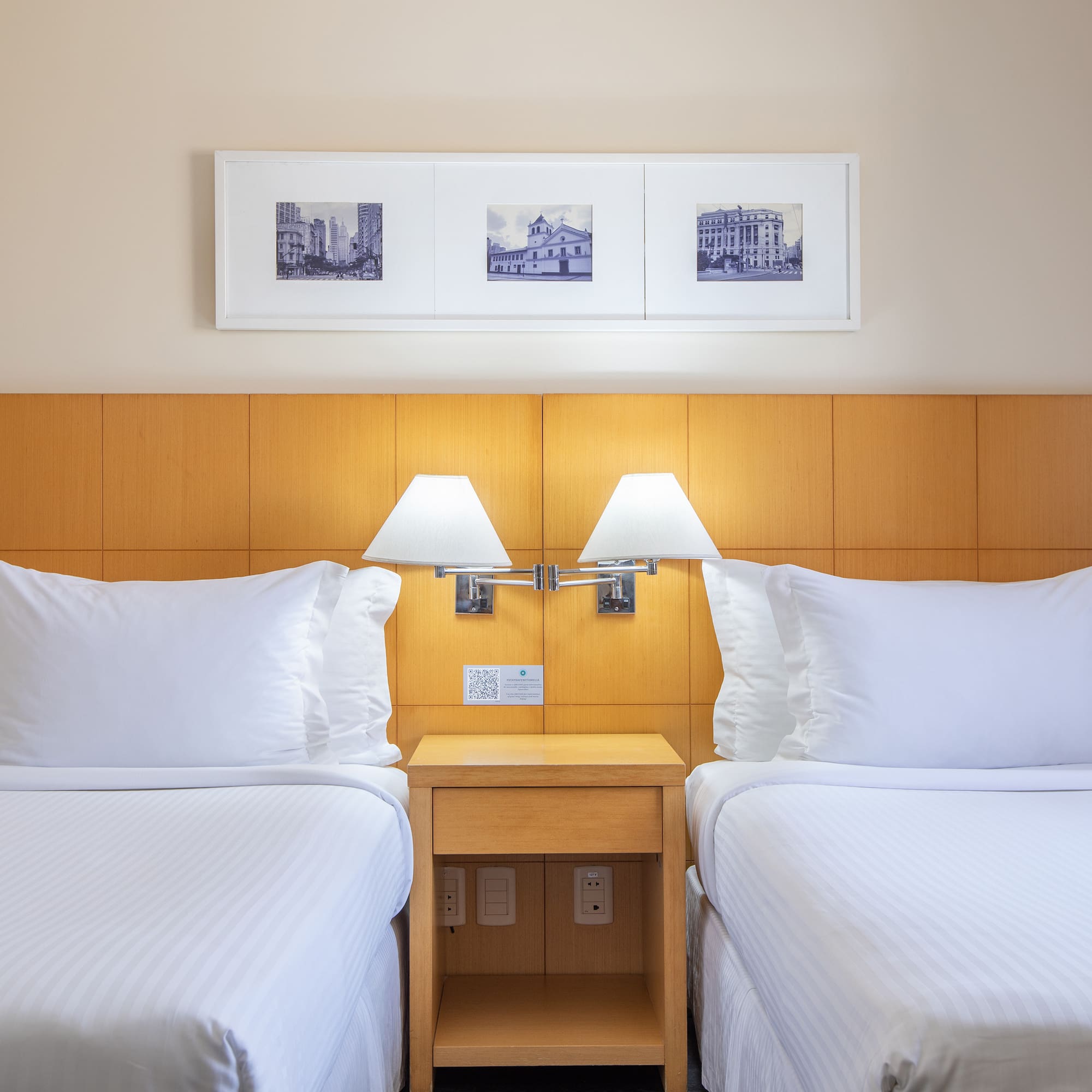 two beds with white sheets and lamps in a hotel room