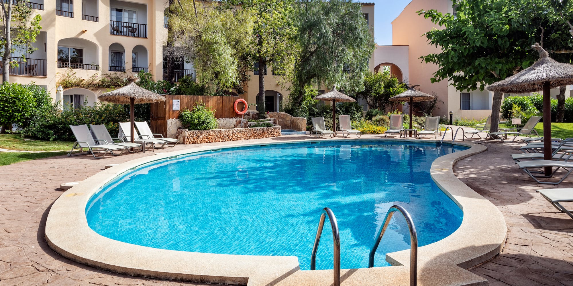 a swimming pool with umbrellas and chairs in front of a building