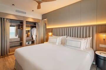 a bed with white sheets and a closet in the background