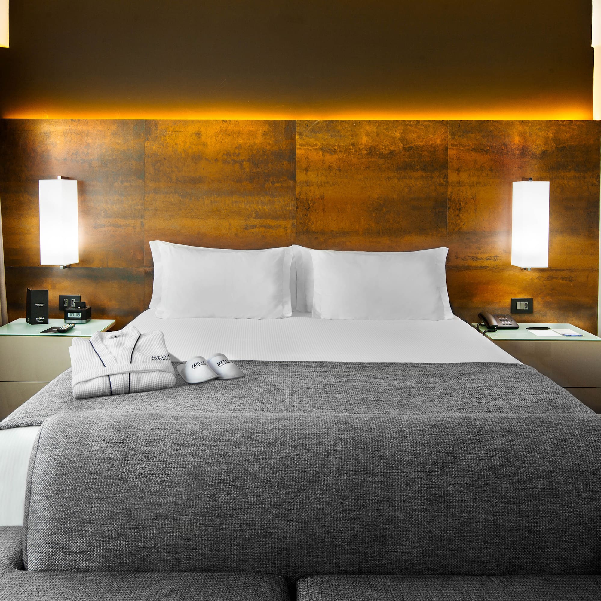 a bed with a grey blanket and pillows