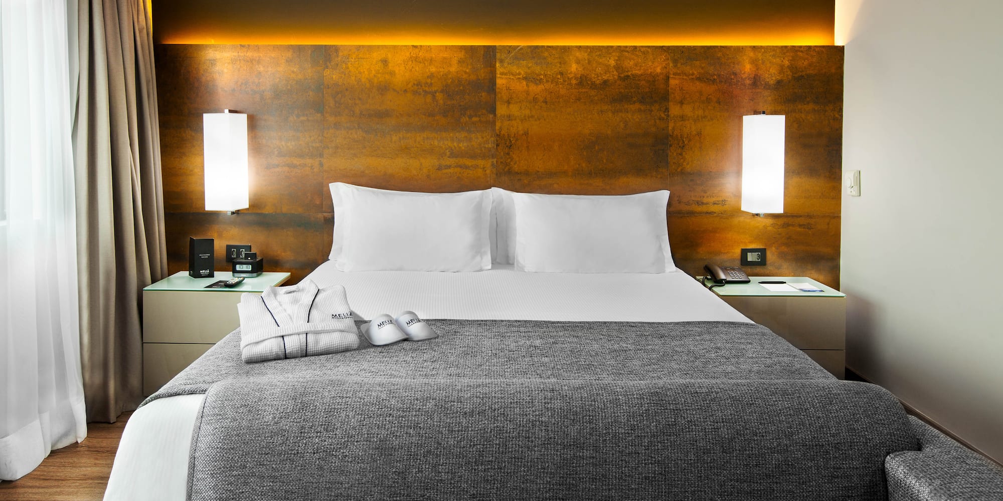 a bed with a grey blanket and pillows