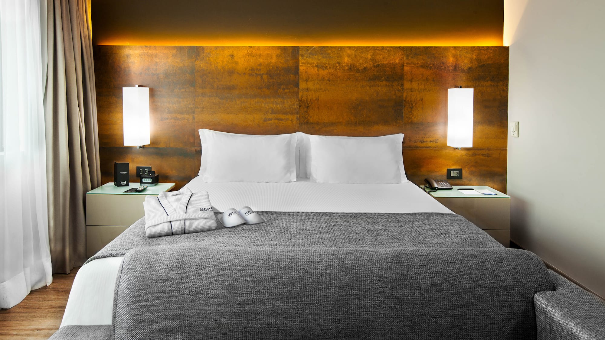 a bed with a grey blanket and pillows