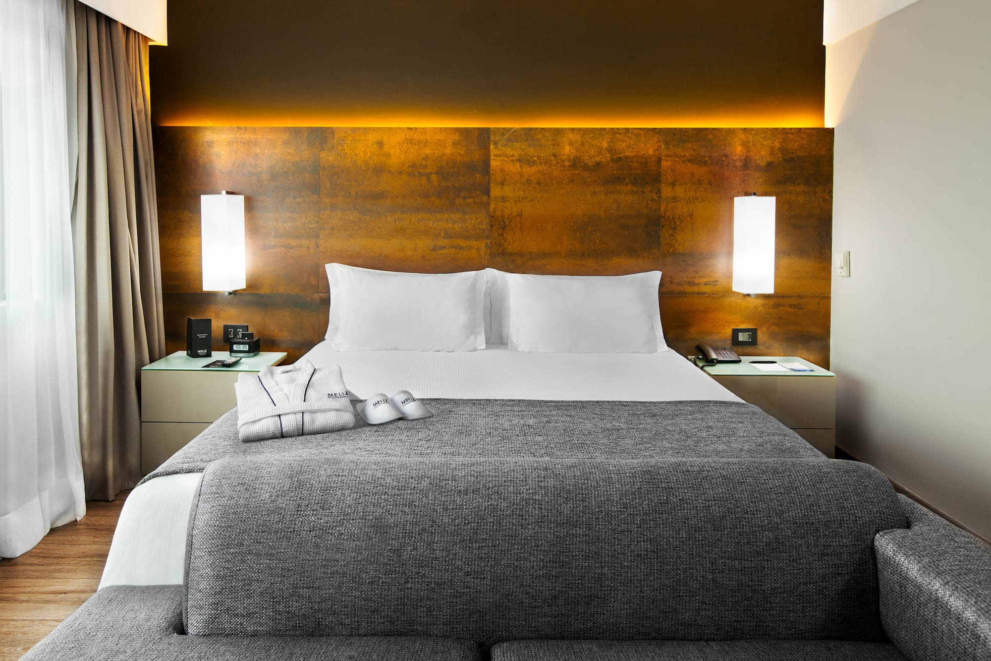 a bed with a grey blanket and pillows