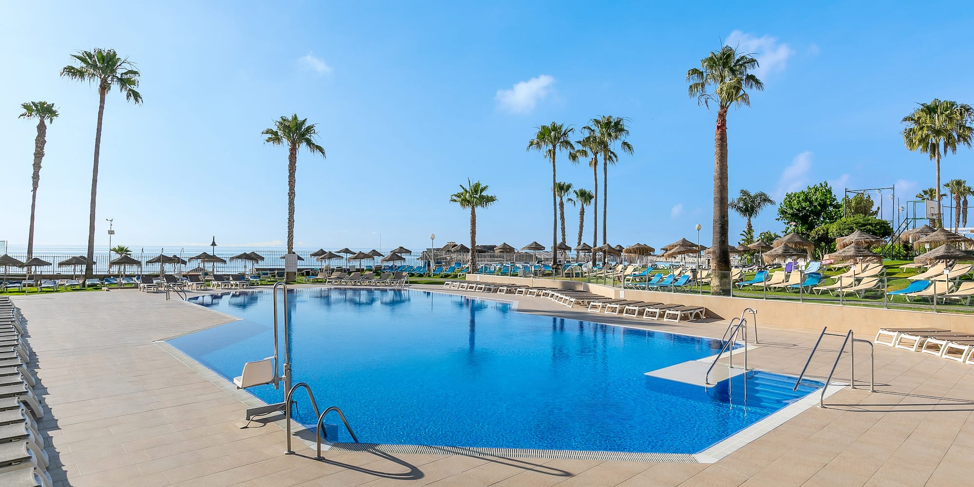 a pool with palm trees and umbrellas