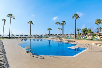 a pool with palm trees and umbrellas