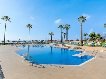 a pool with palm trees and umbrellas