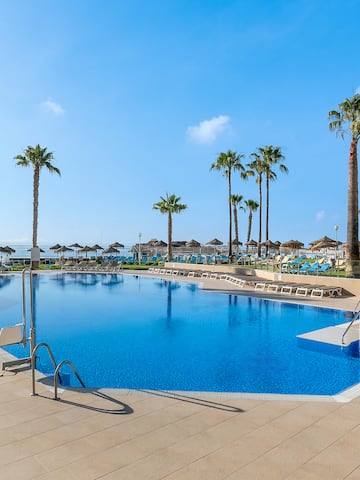 a pool with palm trees and umbrellas