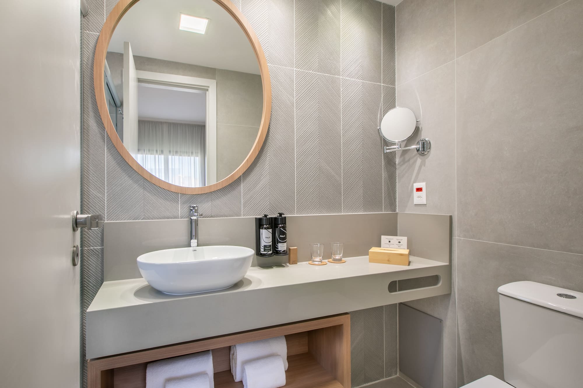 a bathroom with a round mirror and a sink