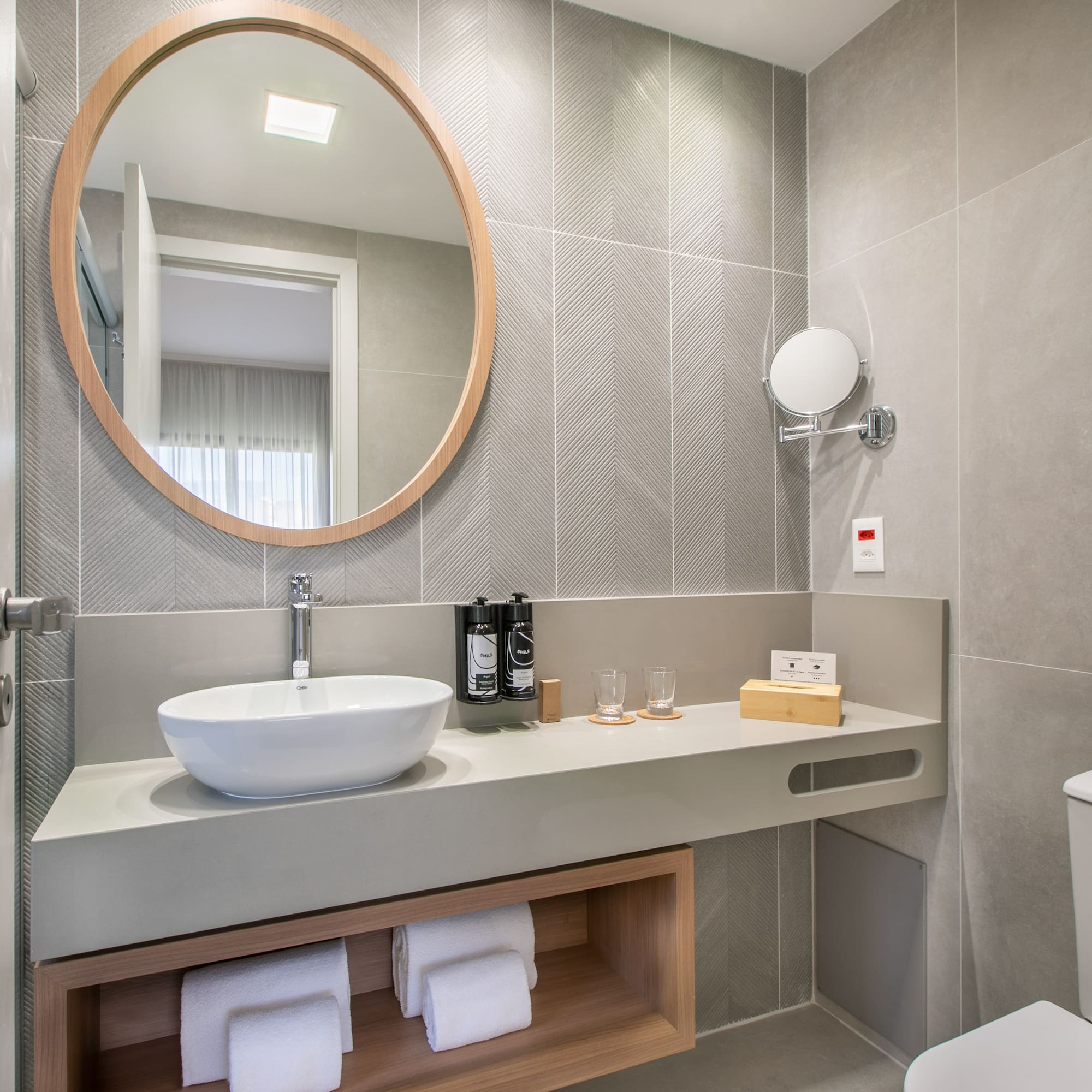 a bathroom with a round mirror and a sink