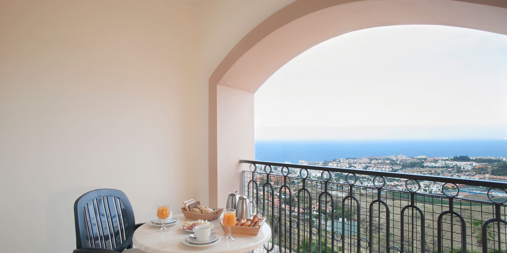 a table with food on it and chairs on a balcony overlooking the ocean