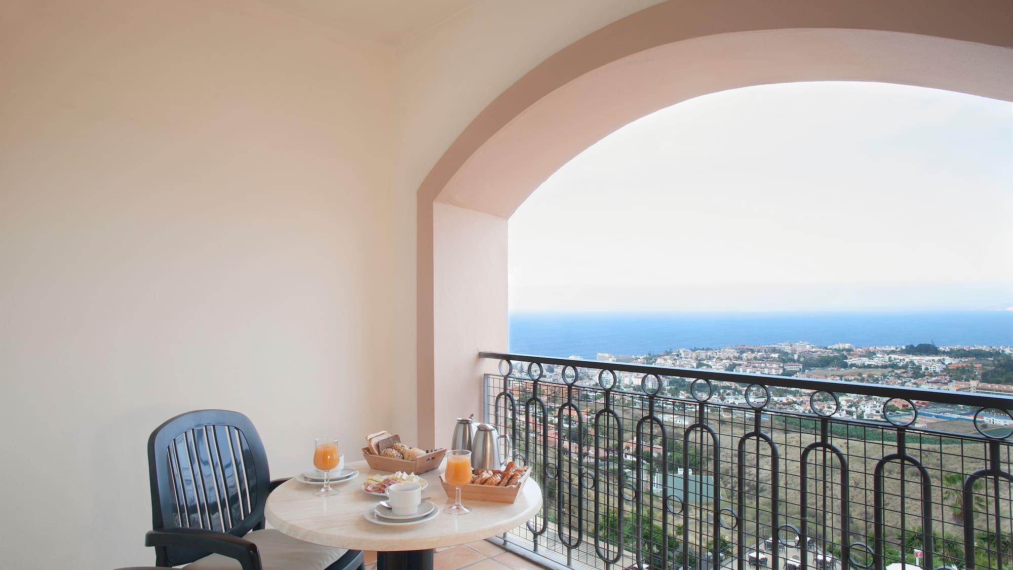 a table with food on it and chairs on a balcony overlooking the ocean