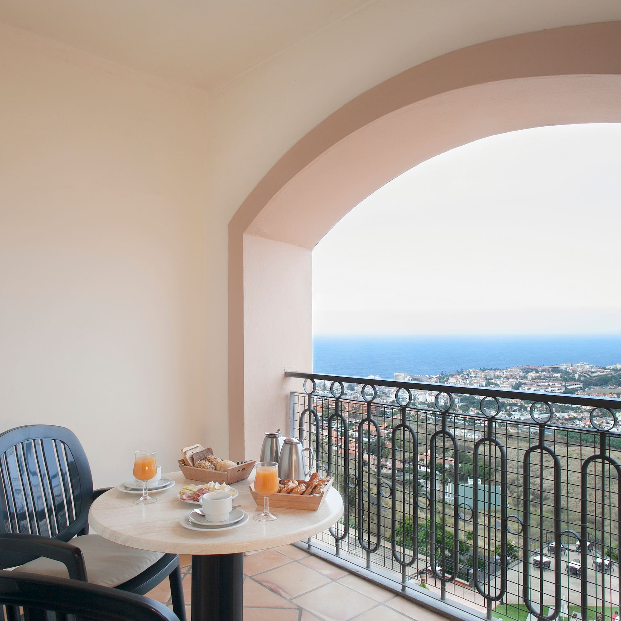 a table with food on it and chairs on a balcony overlooking the ocean