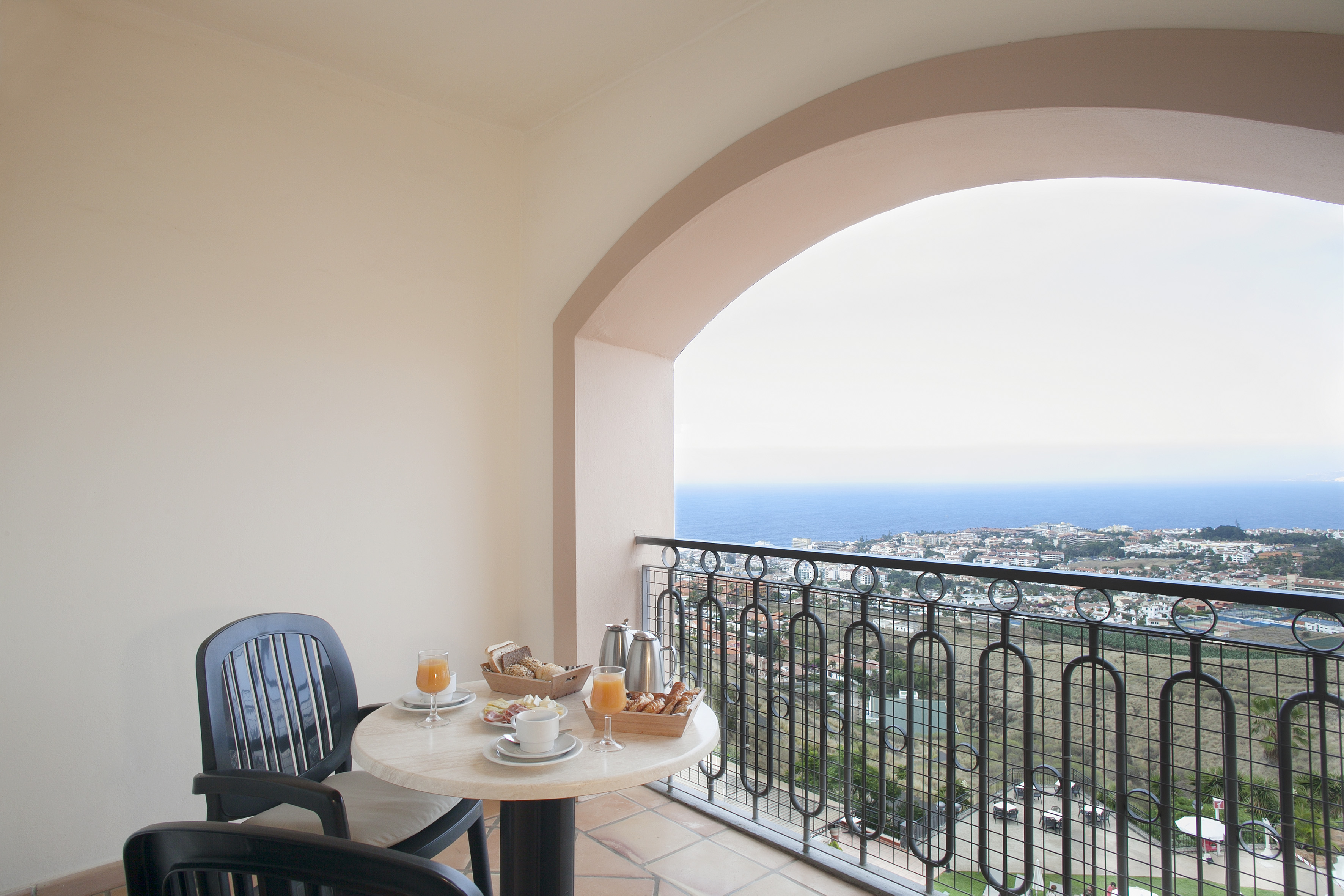 Hotel balcony breakfast overlooking ocean and coastal town.