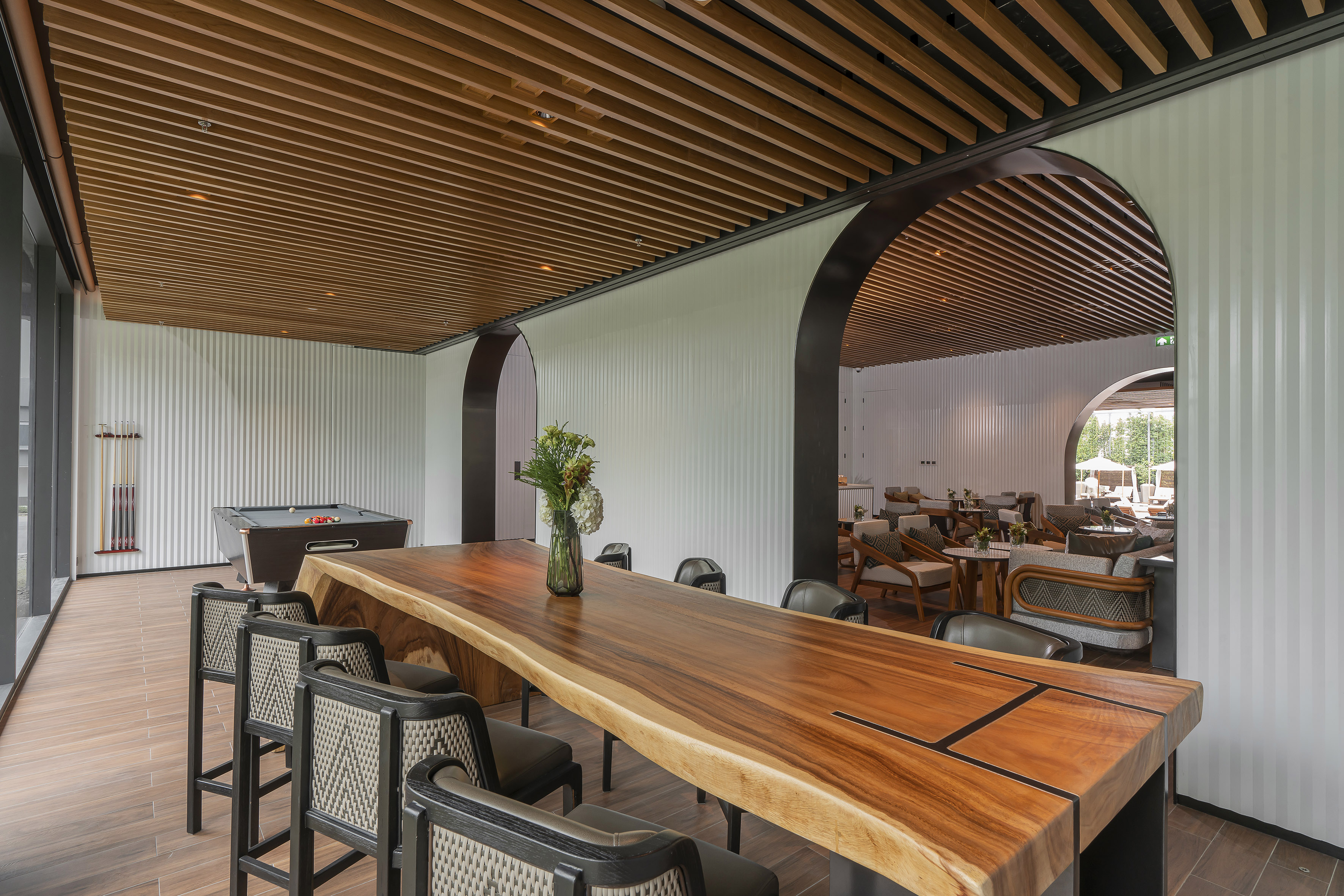 Modern lounge with live-edge wooden table, bar stools, and pool table.