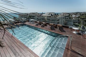 a pool with chairs and a deck overlooking a city