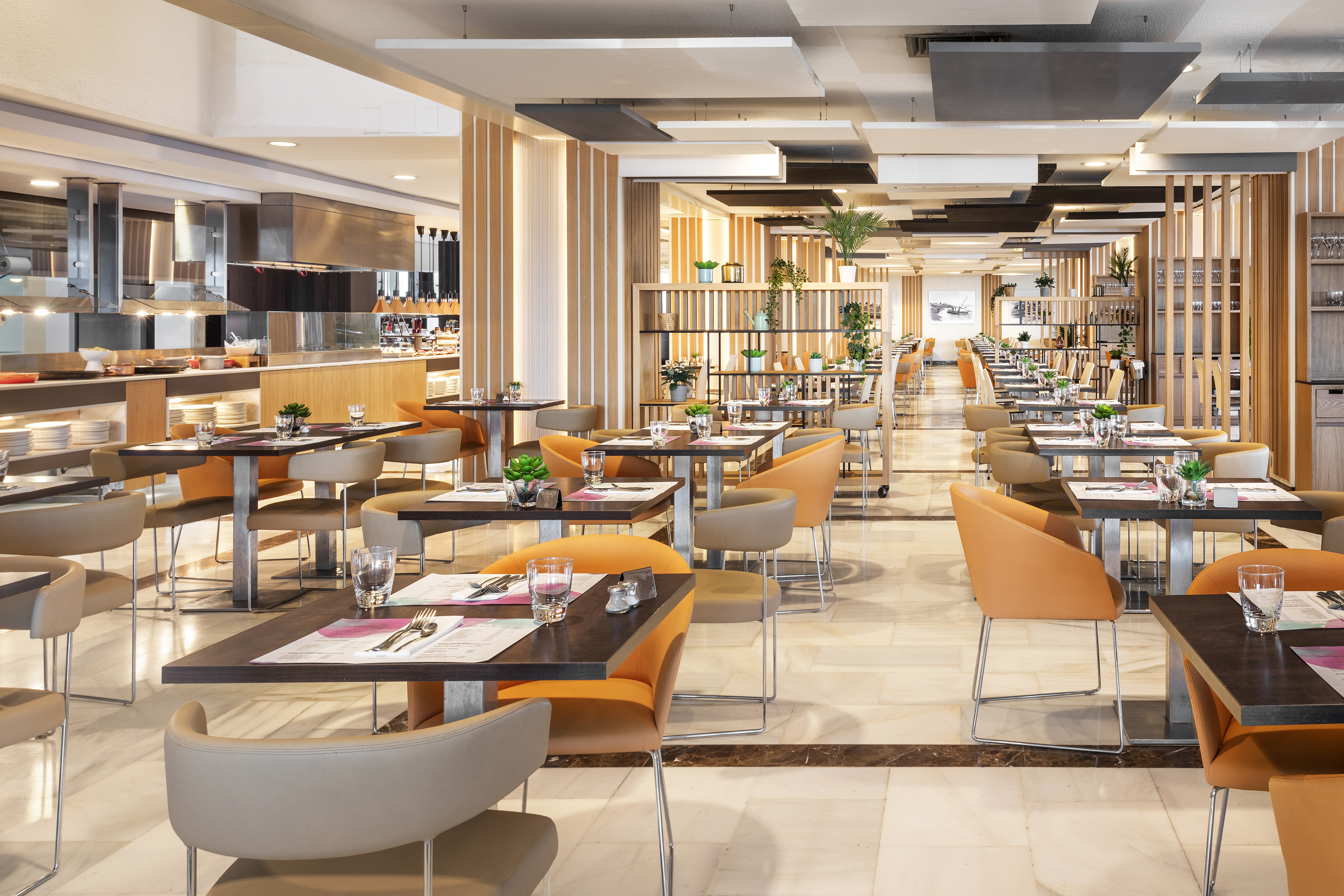 Modern hotel dining room with buffet, wooden accents, and set tables.
