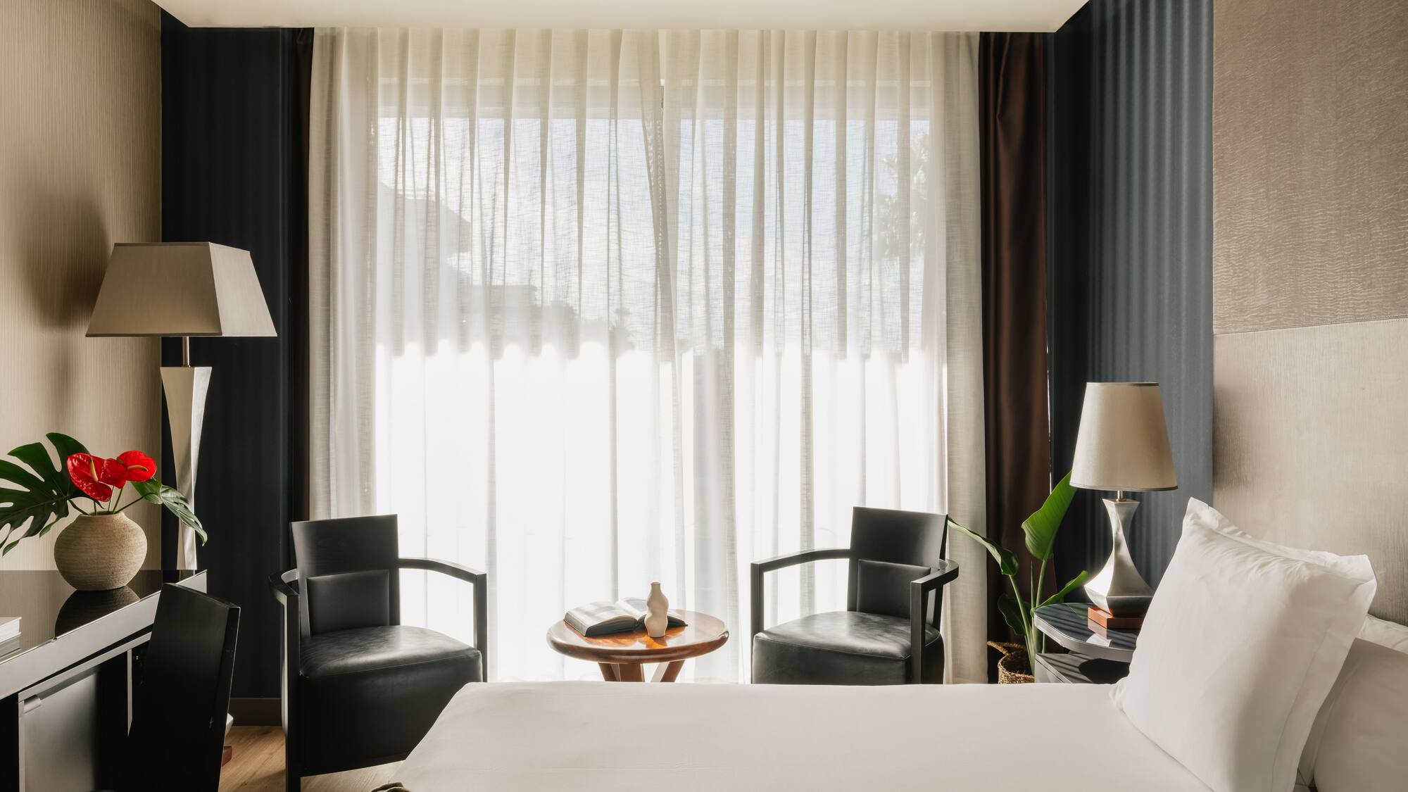 a room with a bed and chairs