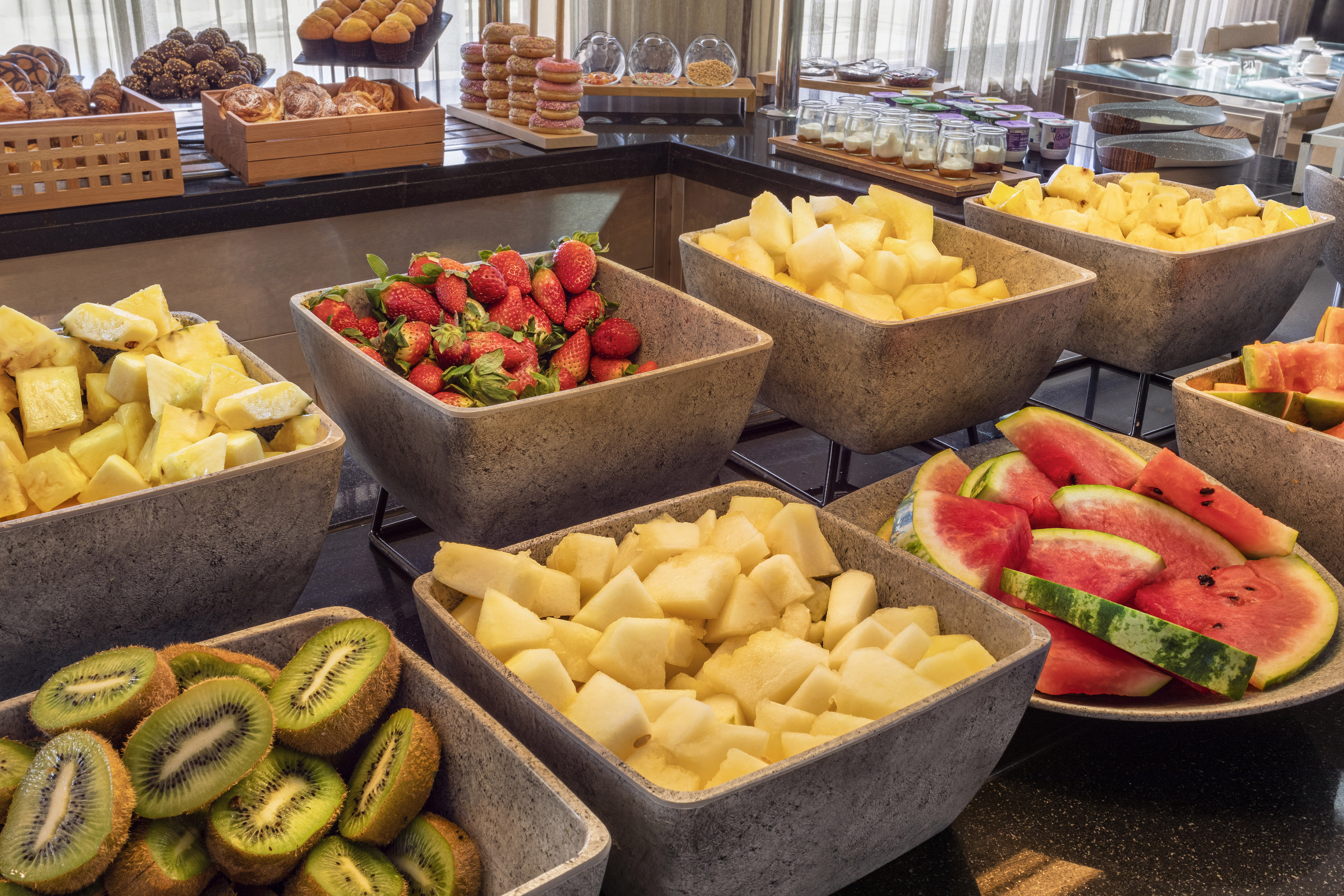 Fresh fruit and pastries on a breakfast buffet spread.