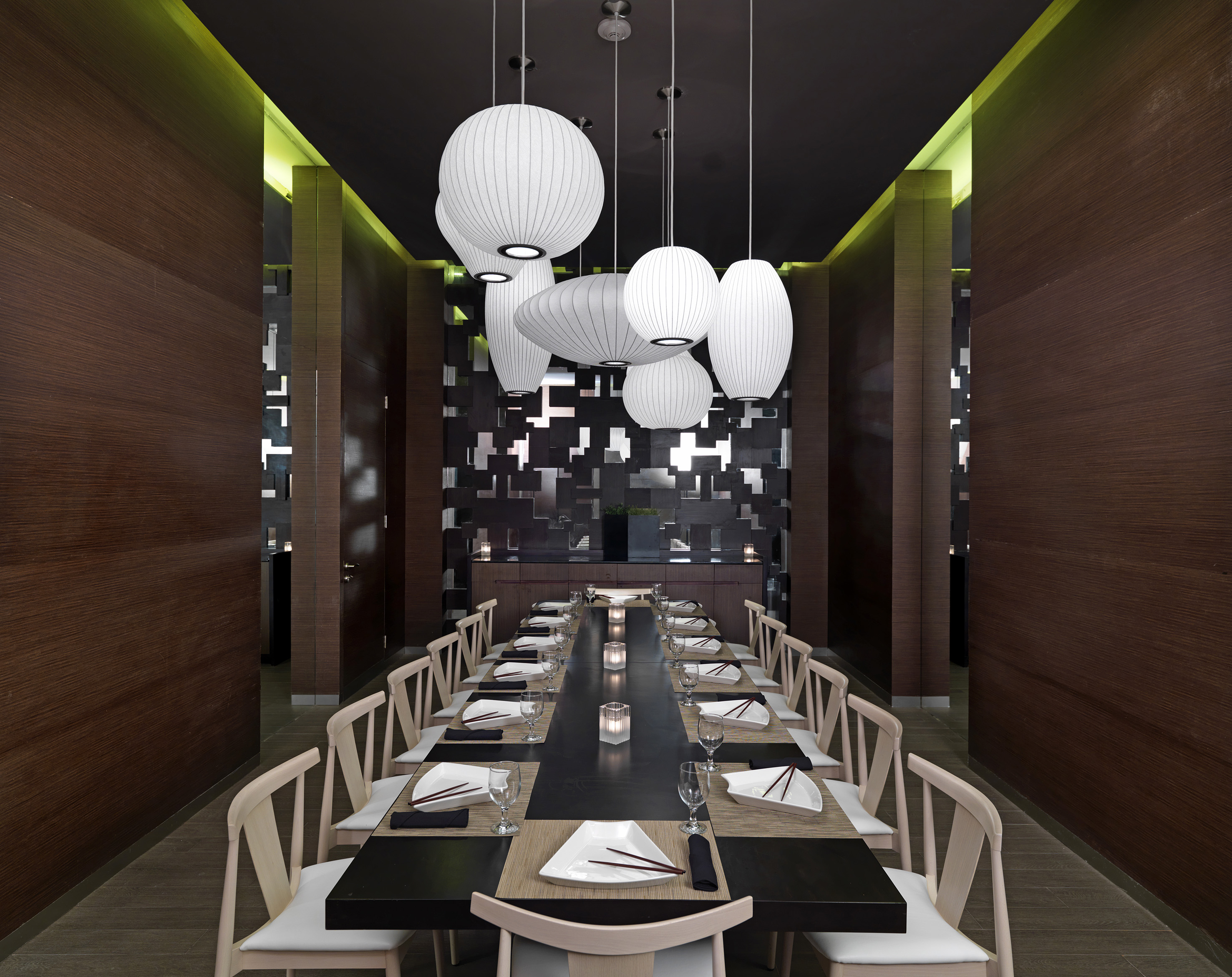 Modern private dining room with long table, pendant lights, and dark wood walls.