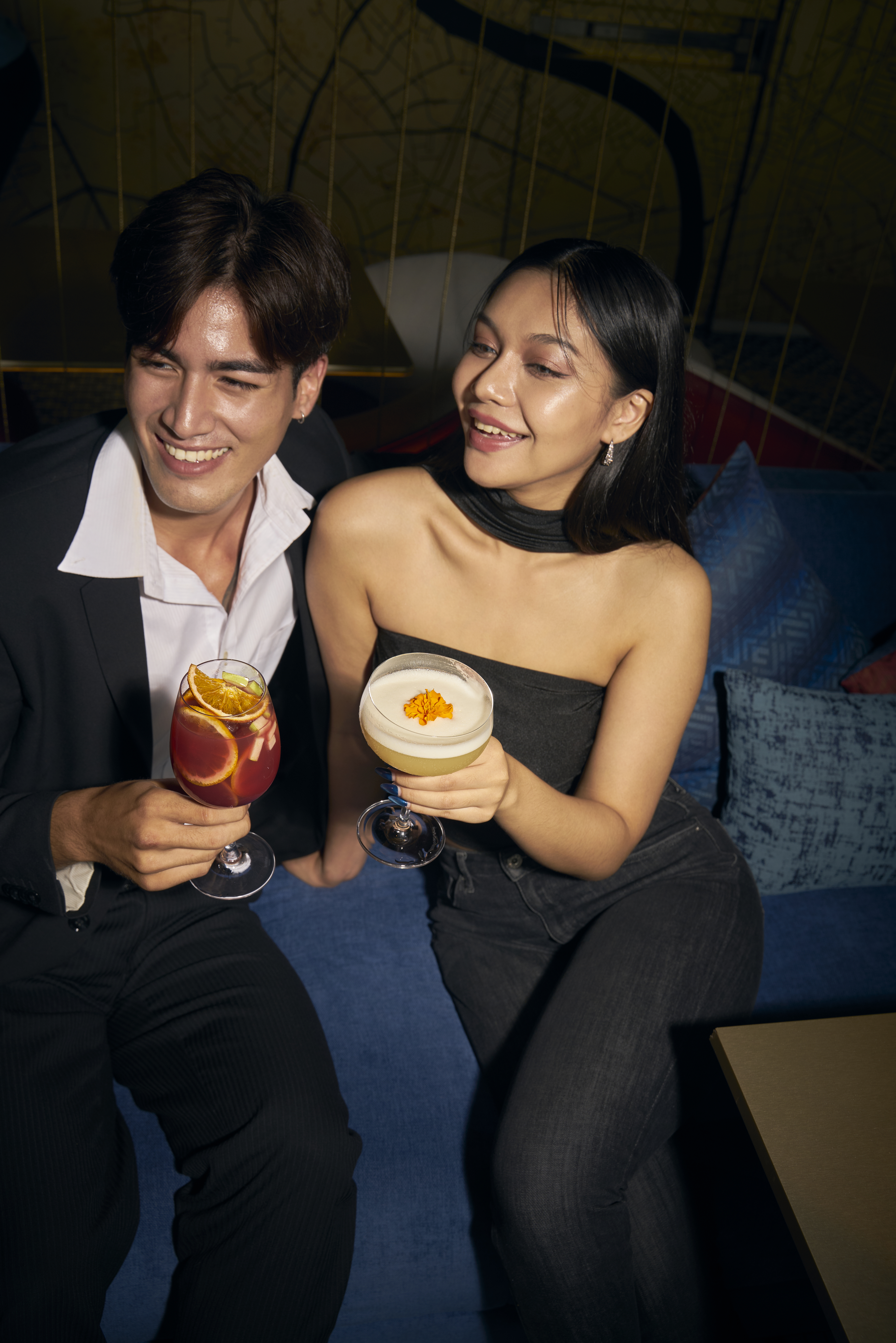 Smiling couple enjoying cocktails at a stylish lounge bar.