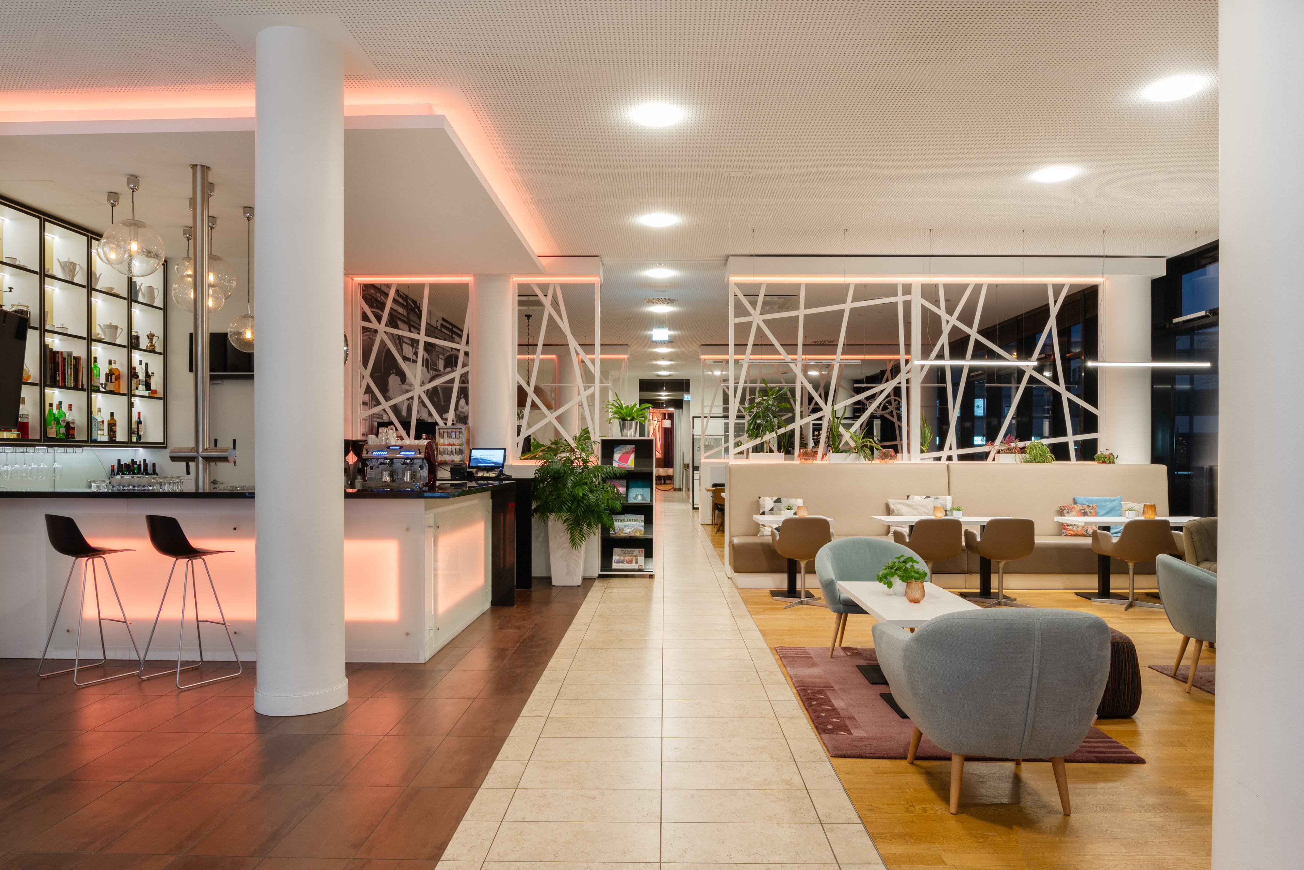 Modern hotel bar and lounge with geometric dividers and diverse seating. - Lobby Lounge Bar, Aperitivos - INNSiDE Wolfsburg, Wolfsburg
