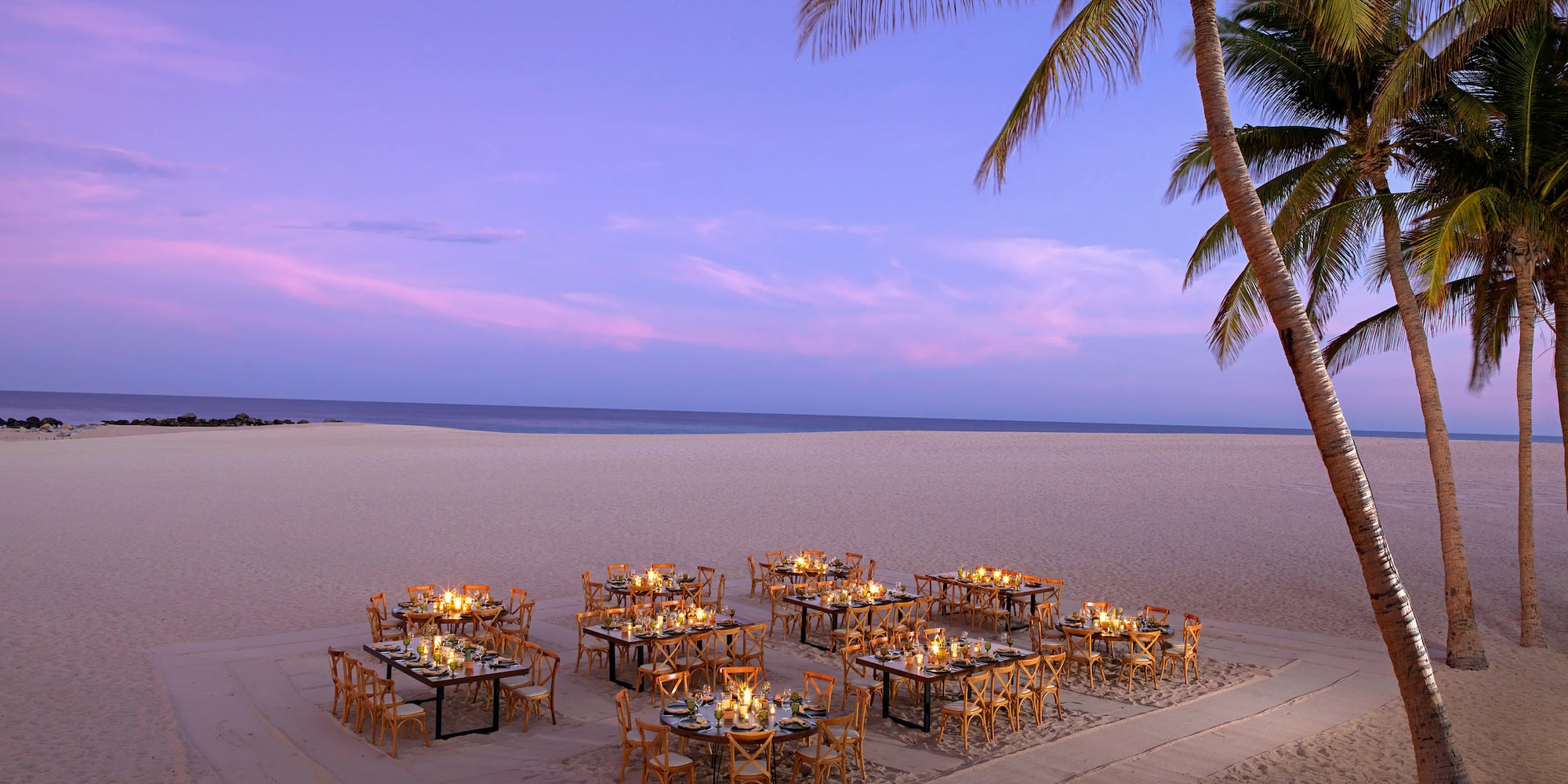 Elegant candlelit beach dining tables with palm trees at twilight, ocean view. - Kanna Beach - Paradisus Los Cabos - Adults Only, Los Cabos