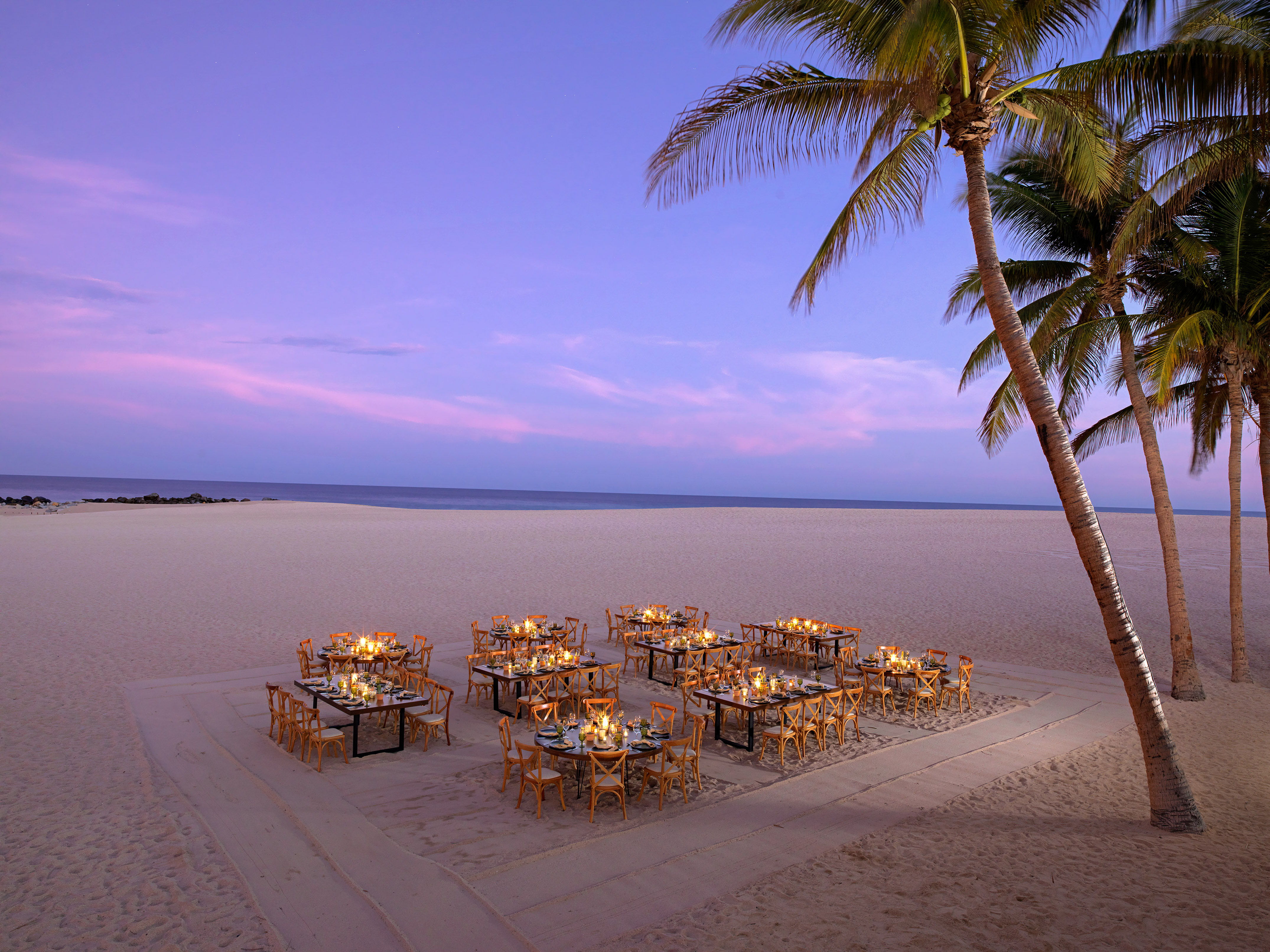 Elegant candlelit beach dining tables with palm trees at twilight, ocean view. - Kanna Beach - Paradisus Los Cabos - Adults Only, Los Cabos