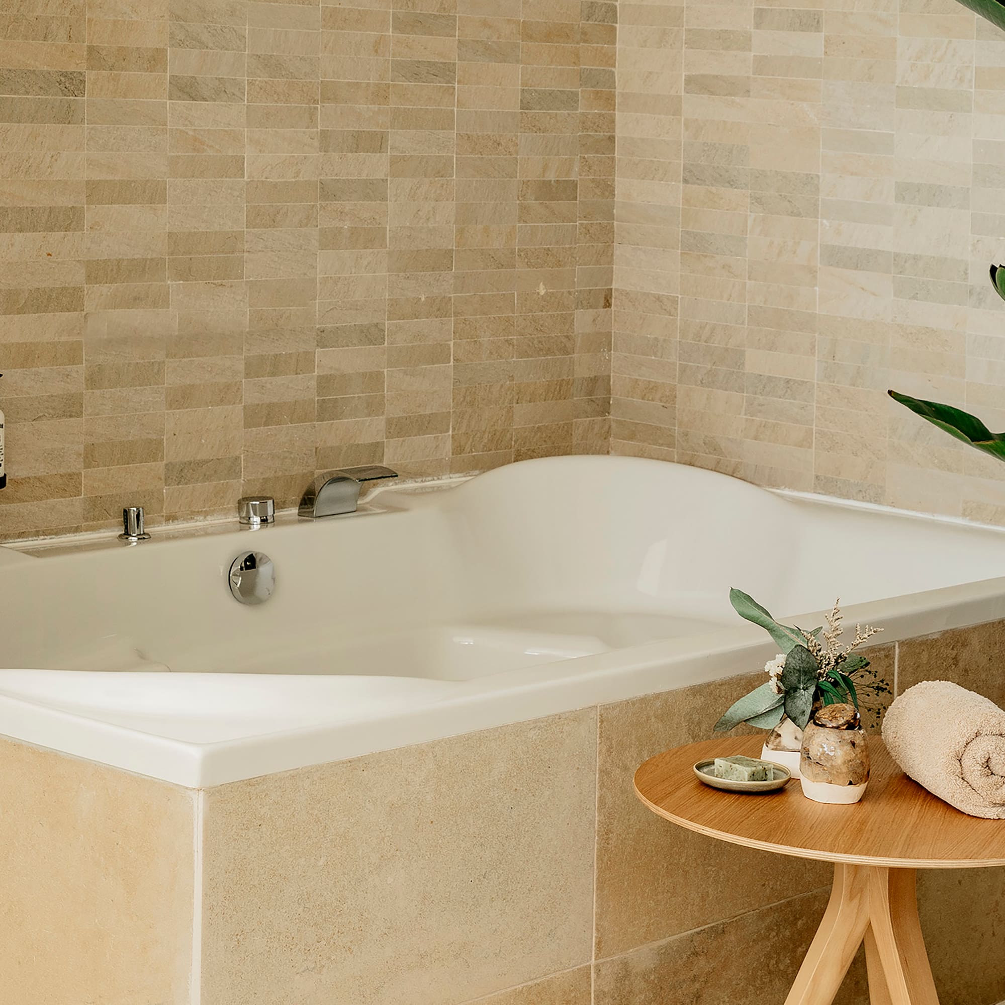 a bathtub with a small table and a plant