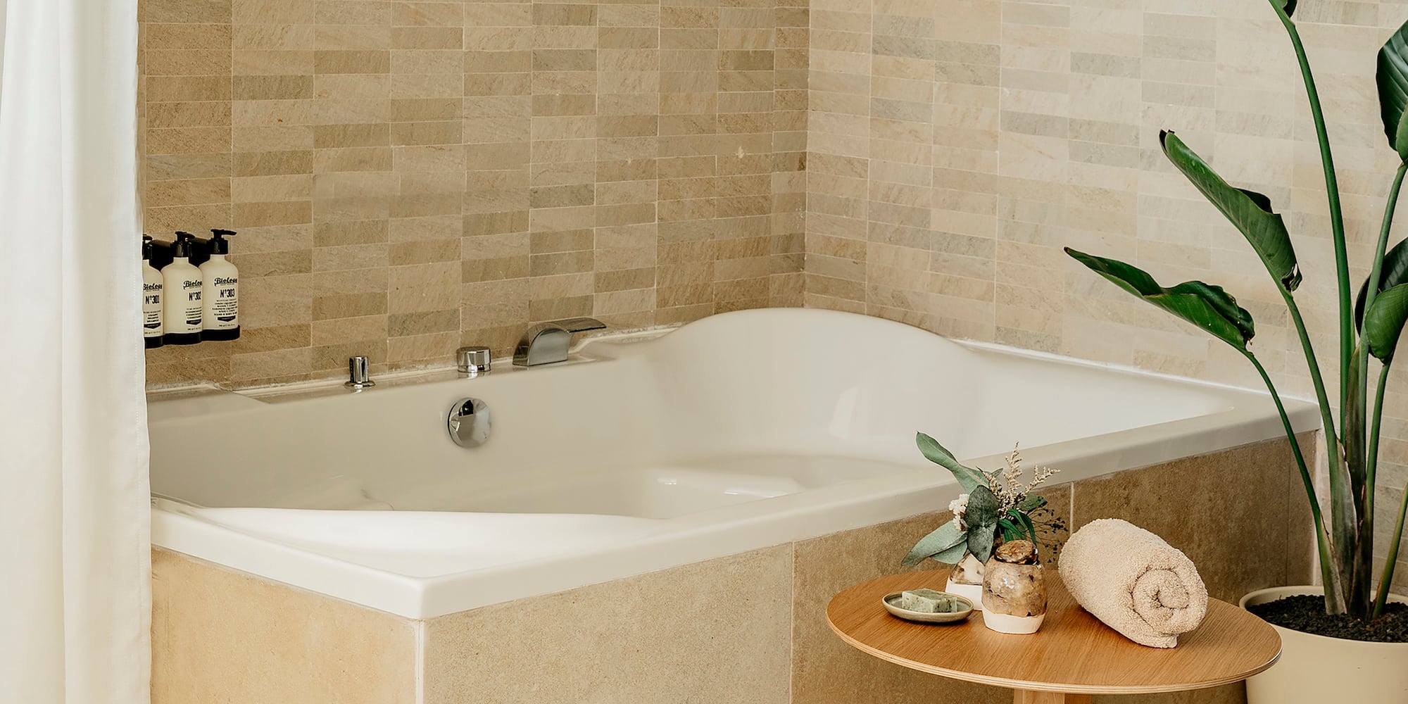 a bathtub with a small table and a plant