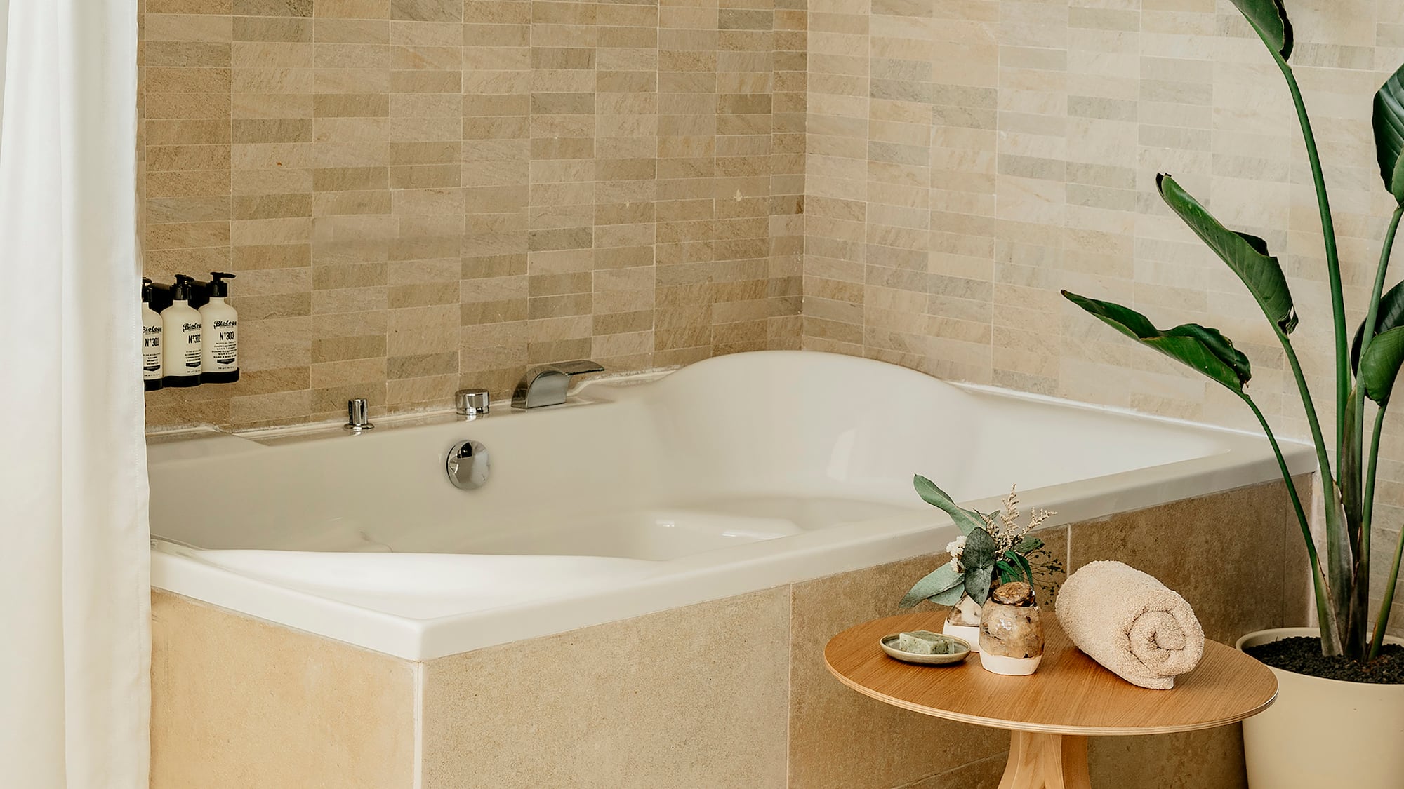 a bathtub with a small table and a plant