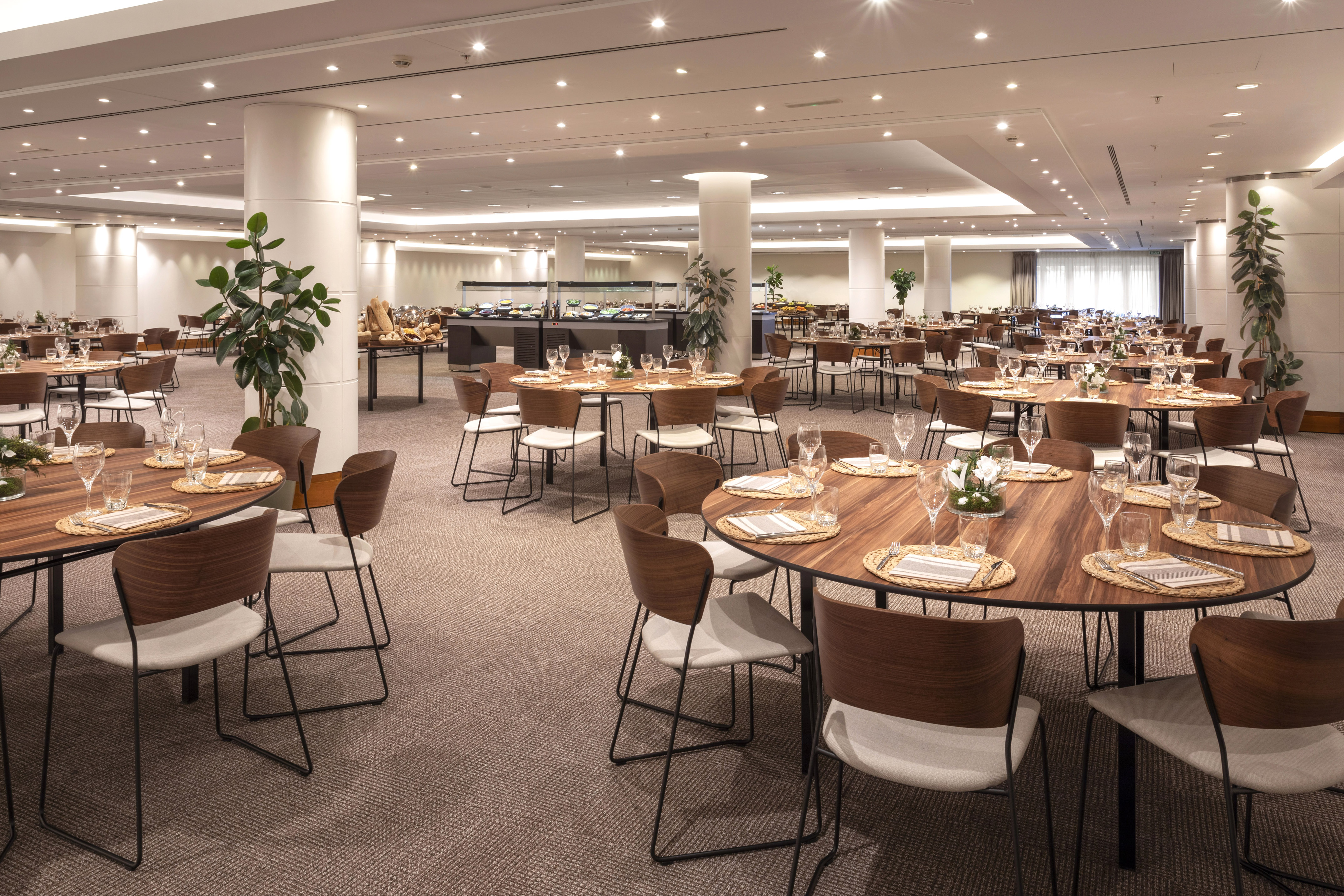 Elegant buffet restaurant with round tables, modern chairs, and food stations.