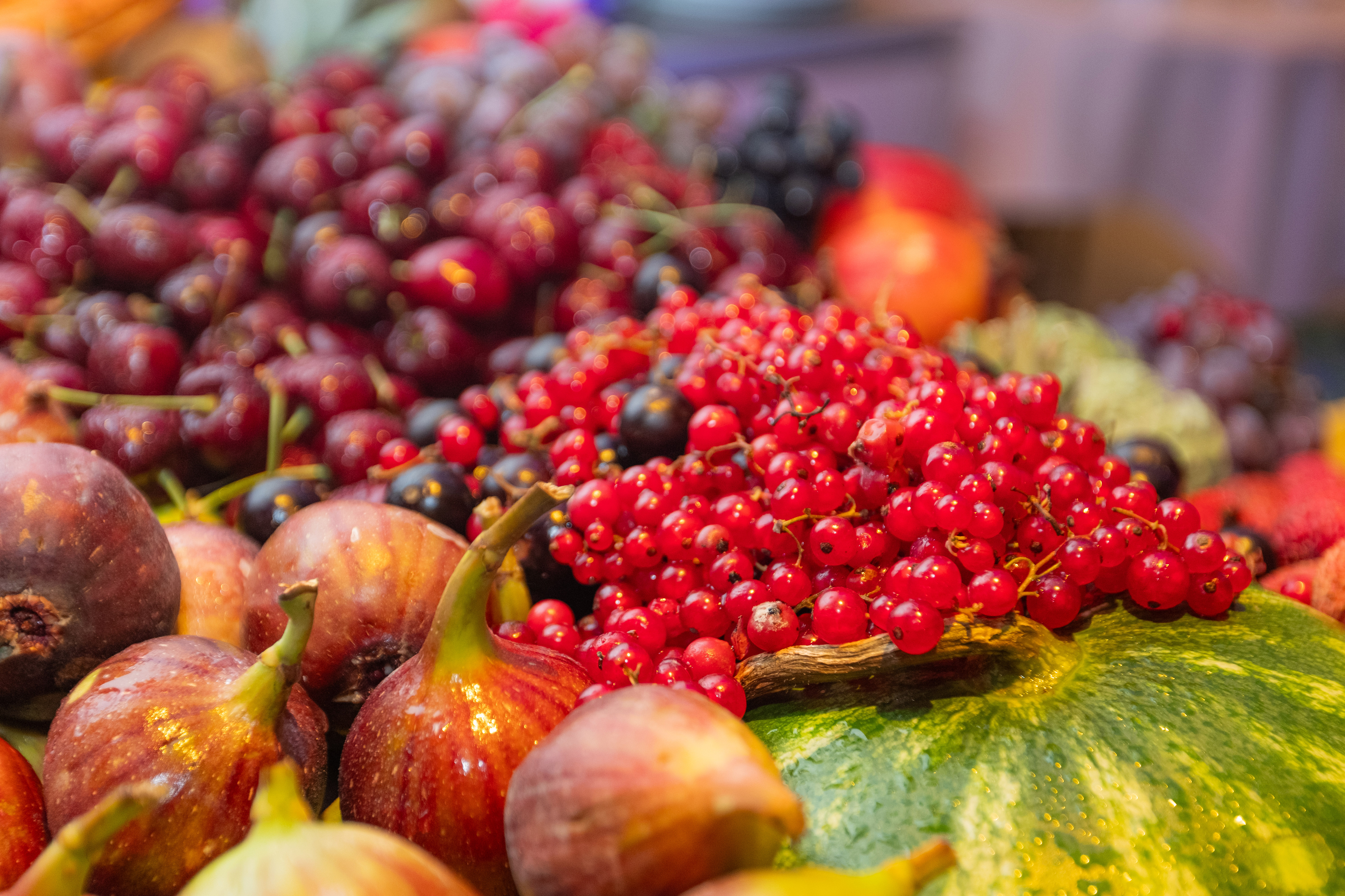 Frutas frescas: grosellas rojas, higos, uvas y sandía en exhibición.