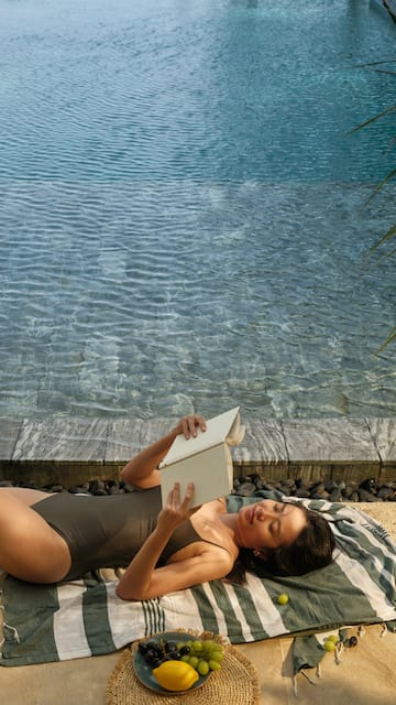 a woman lying on a beach reading a book