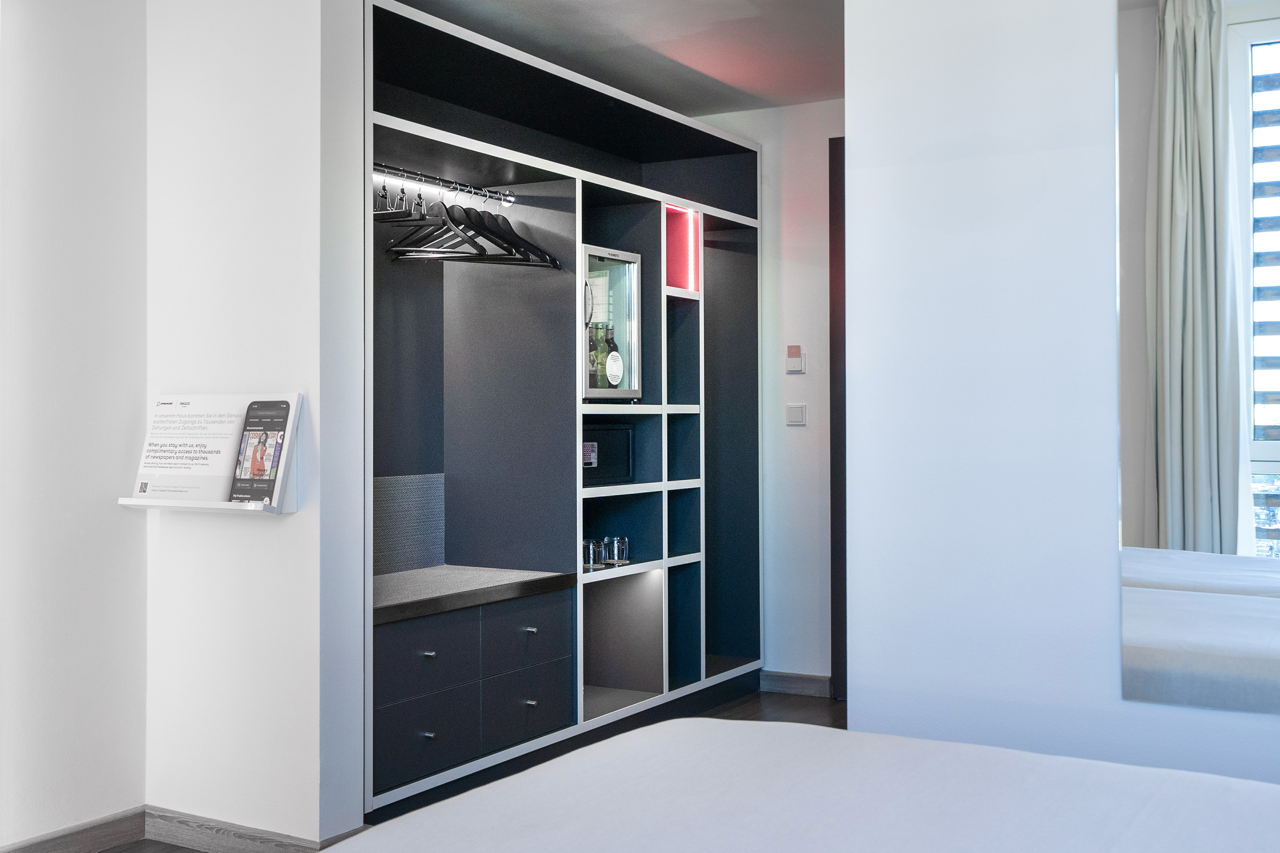 Modern hotel room wardrobe with minibar, safe, and hanging space.