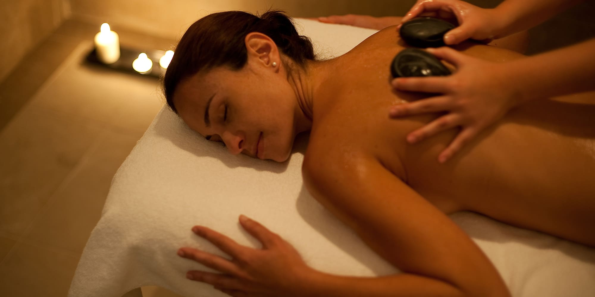 Hot stone massage on a woman's back in a serene spa setting.