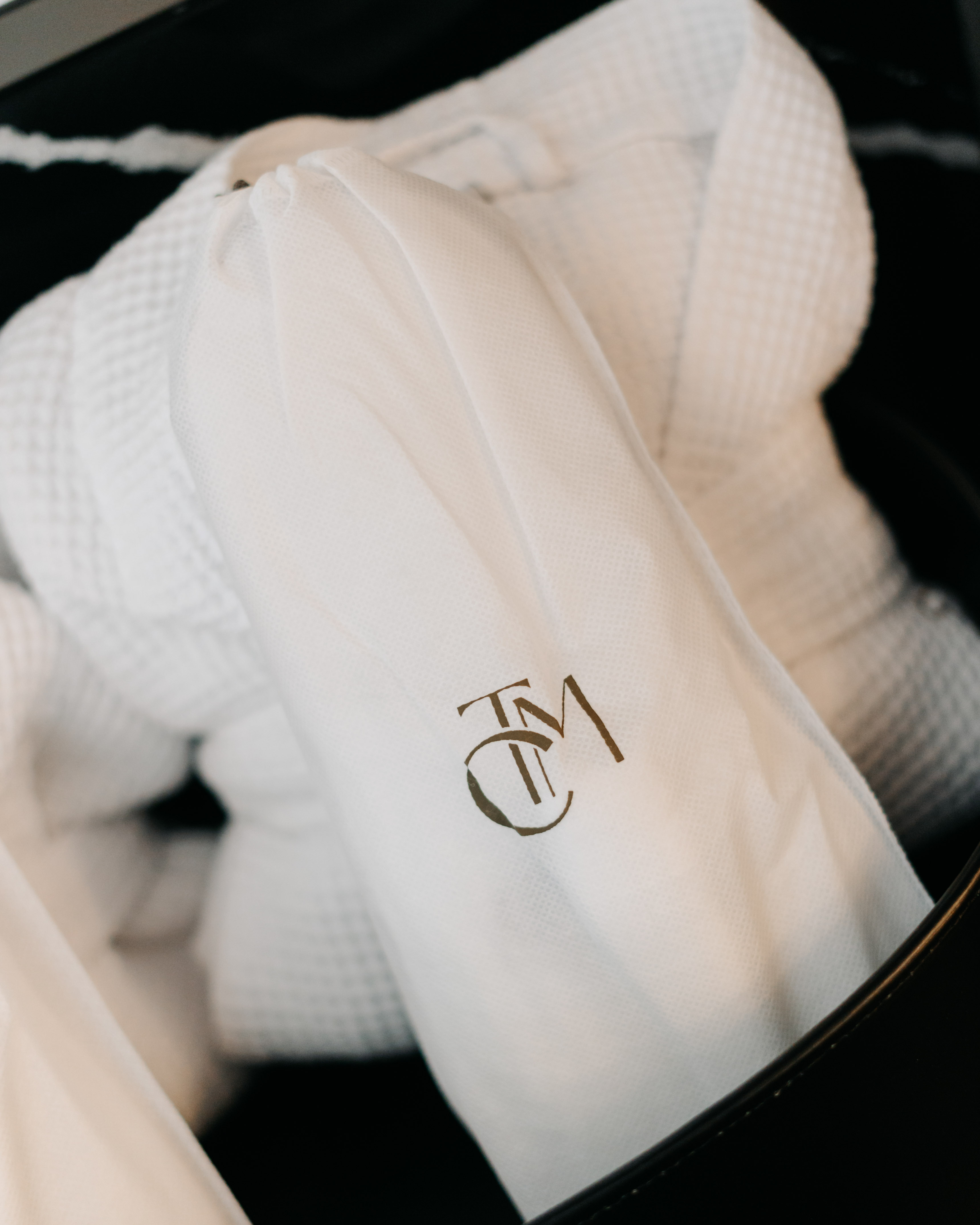 White waffle bathrobe in a logo-embossed white bag, hotel luxury amenity.
