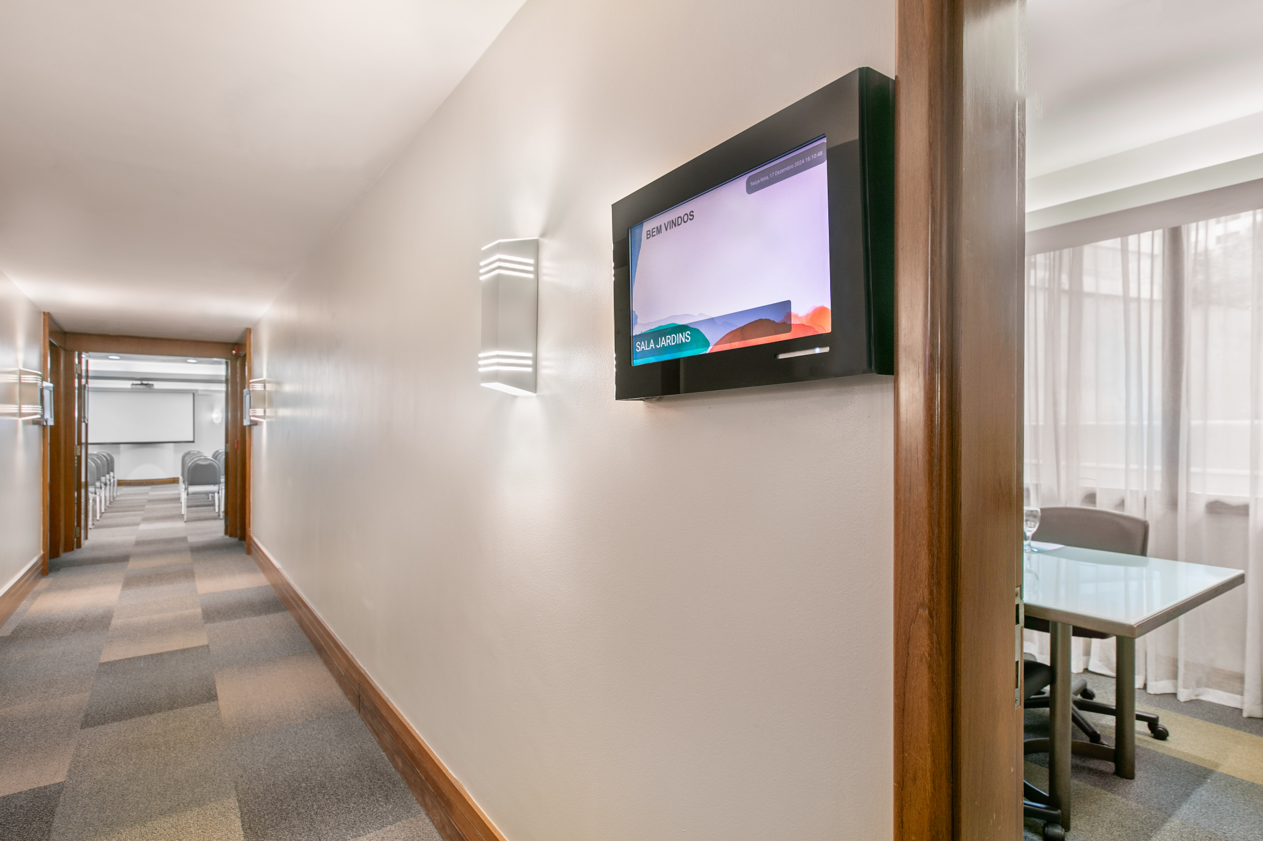 Modern business hallway with digital signage and entrances to conference rooms.