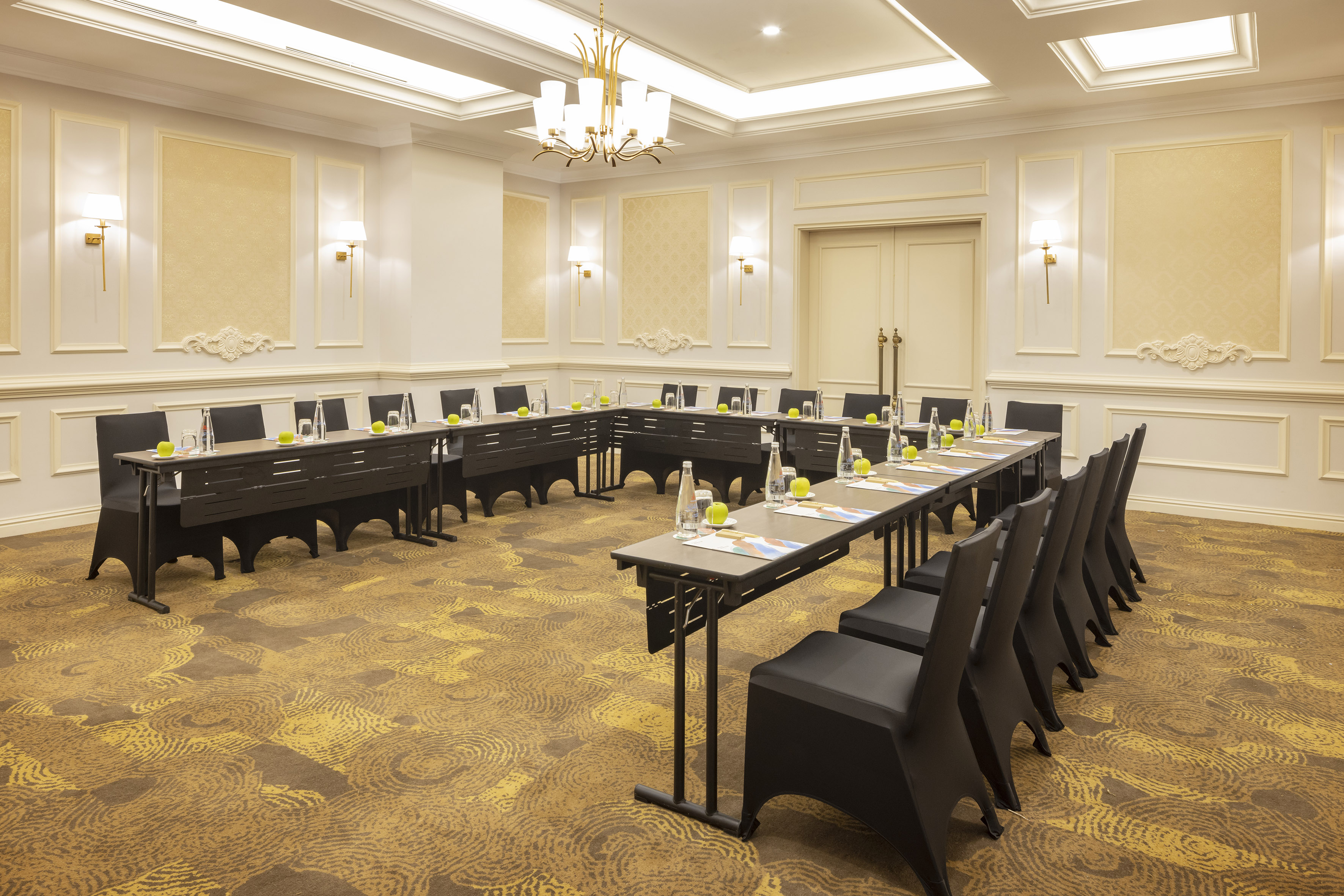 Elegant U-shaped conference room setup with black chairs and refreshments.