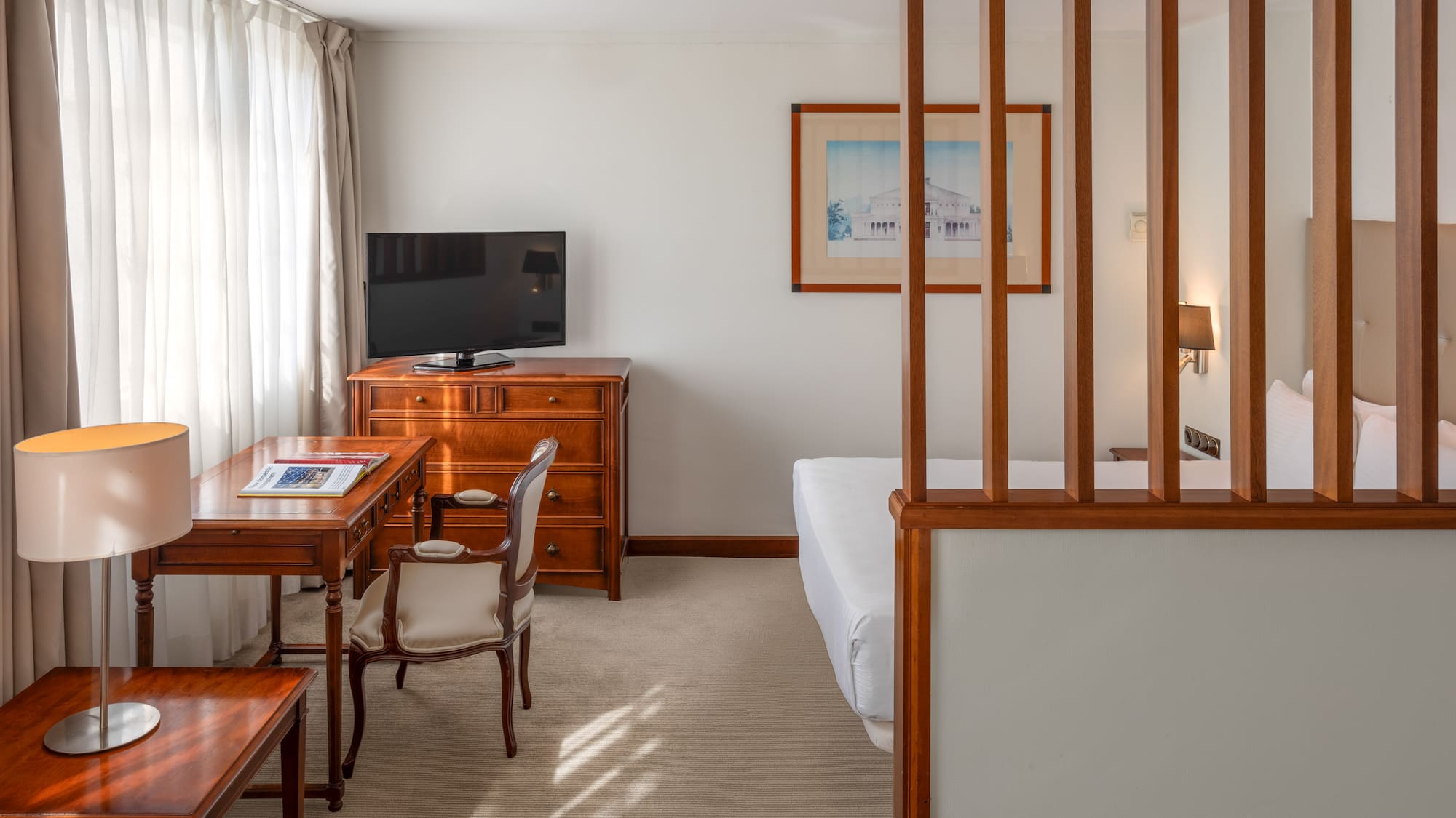Comfortable hotel room with desk, TV, and partitioned sleeping area.