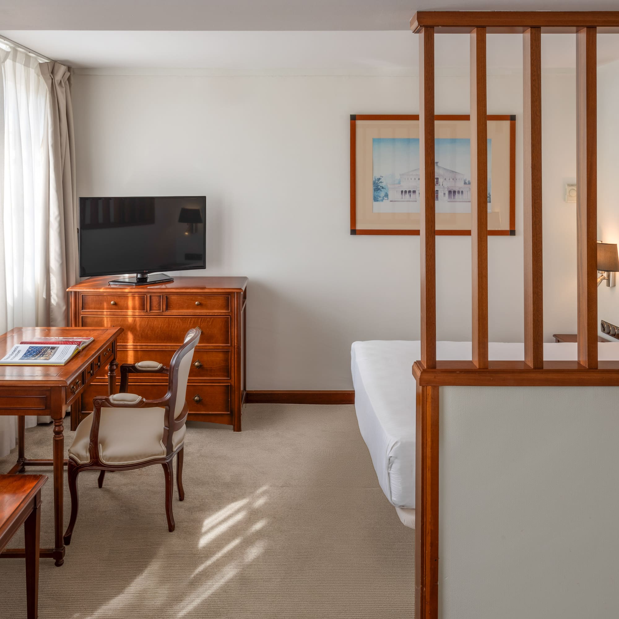 Comfortable hotel room with desk, TV, and partitioned sleeping area.