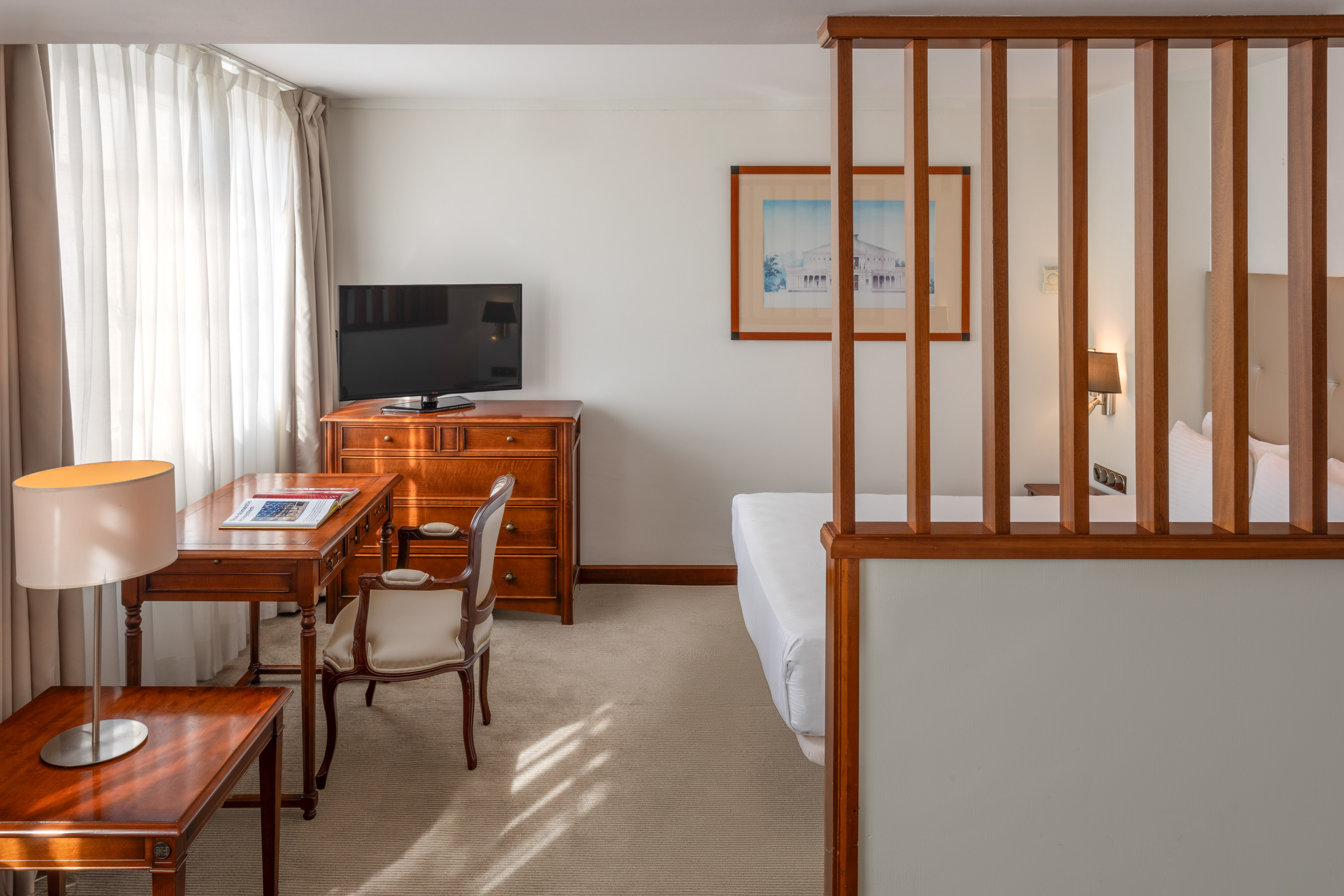 Comfortable hotel room with desk, TV, and partitioned sleeping area.