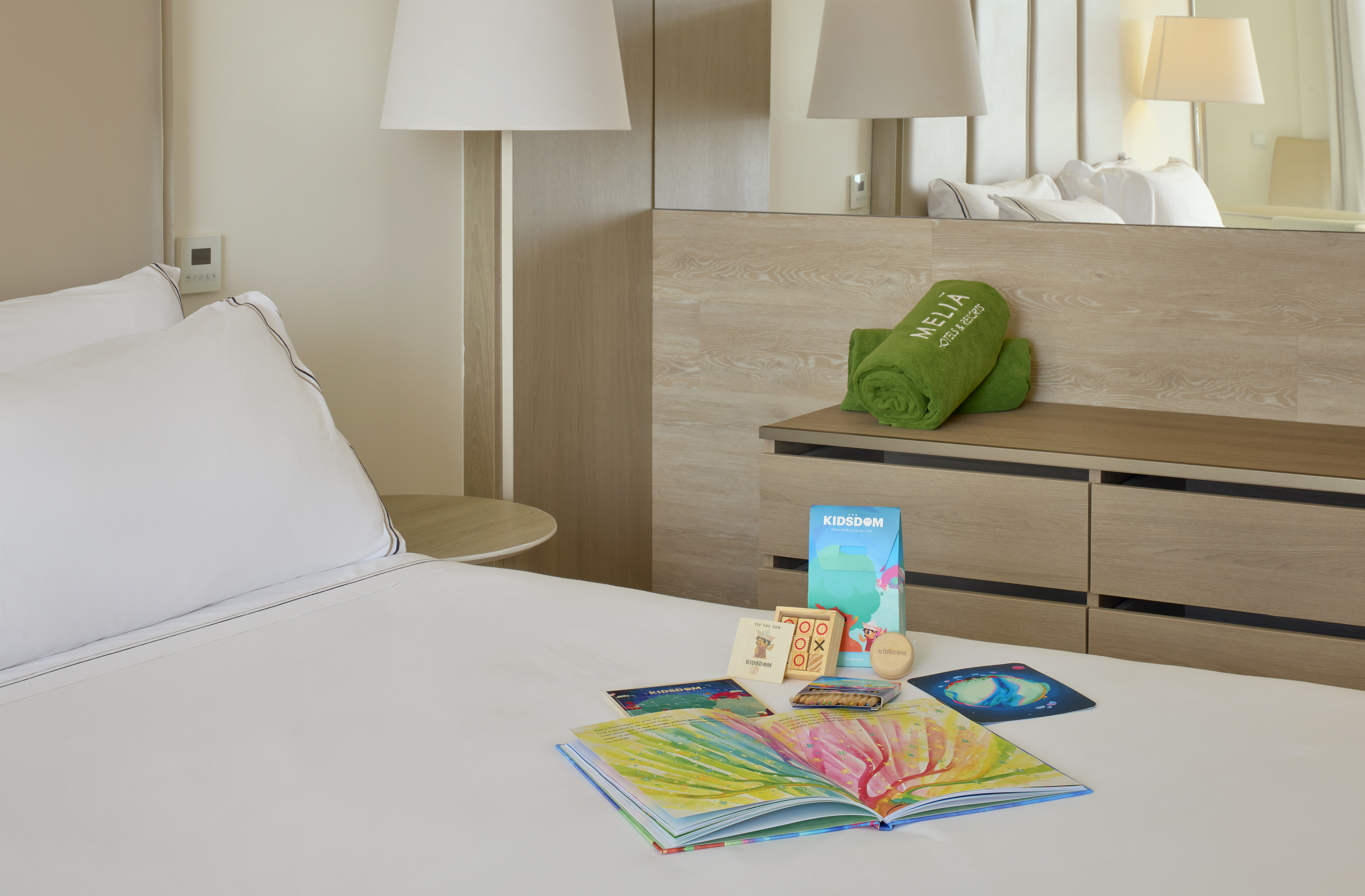 Meliá hotel room, bed with kids' welcome pack: book, game, coloring.