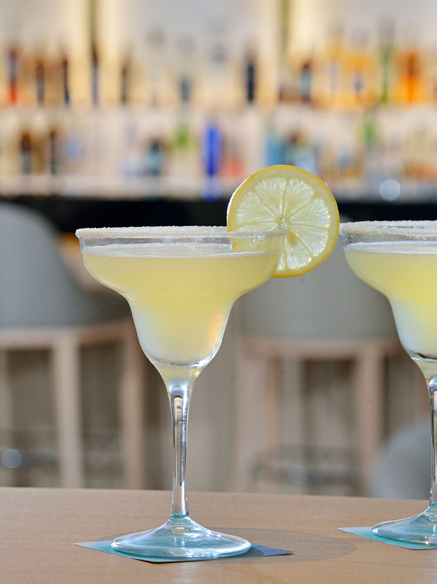 two glasses of yellow liquid with lemon slices on top of them