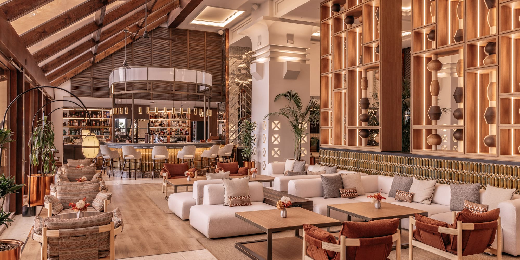 Modern hotel lobby lounge with stylish seating, wooden bar, and accent lighting.