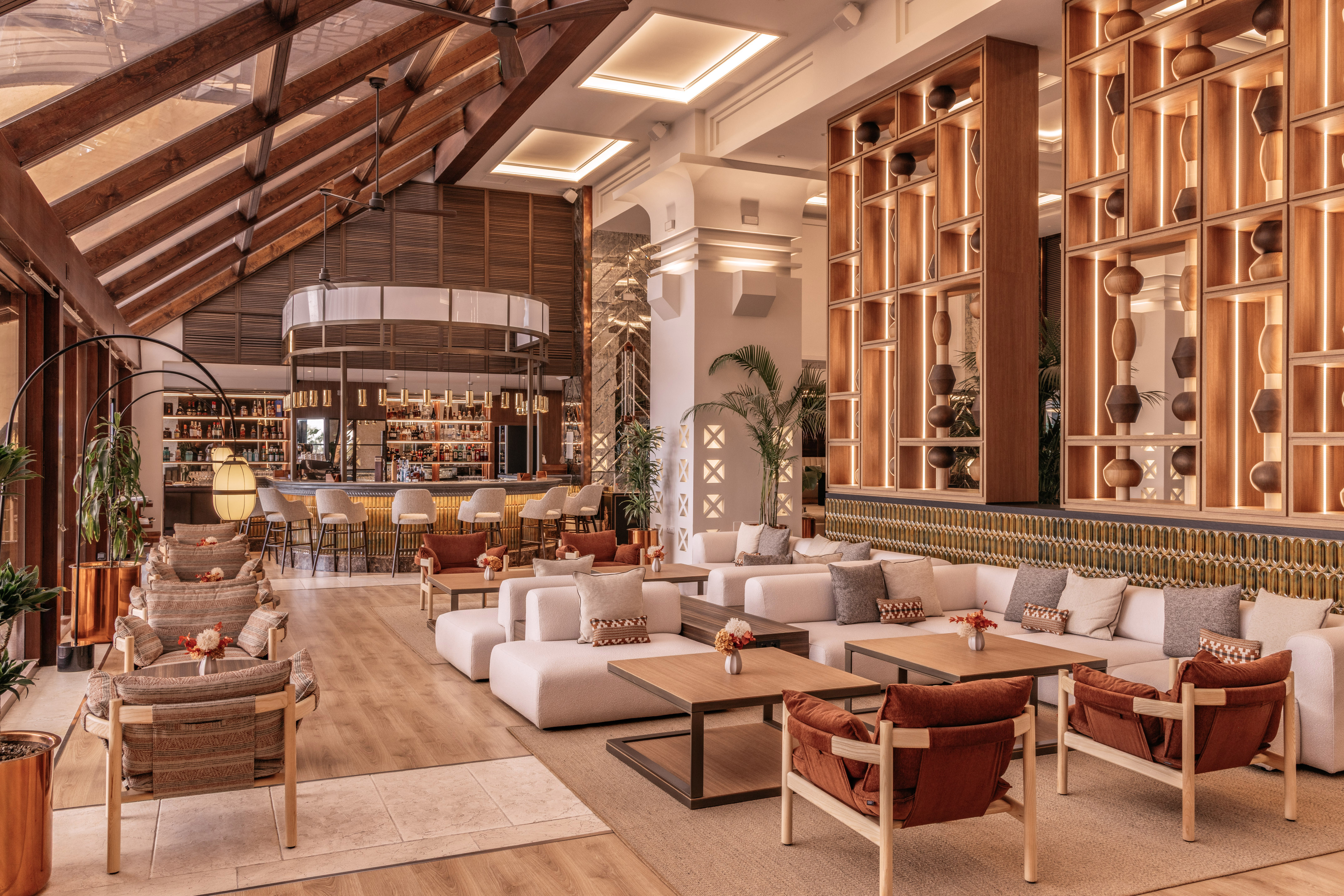 Modern hotel lobby lounge with stylish seating, wooden bar, and accent lighting.