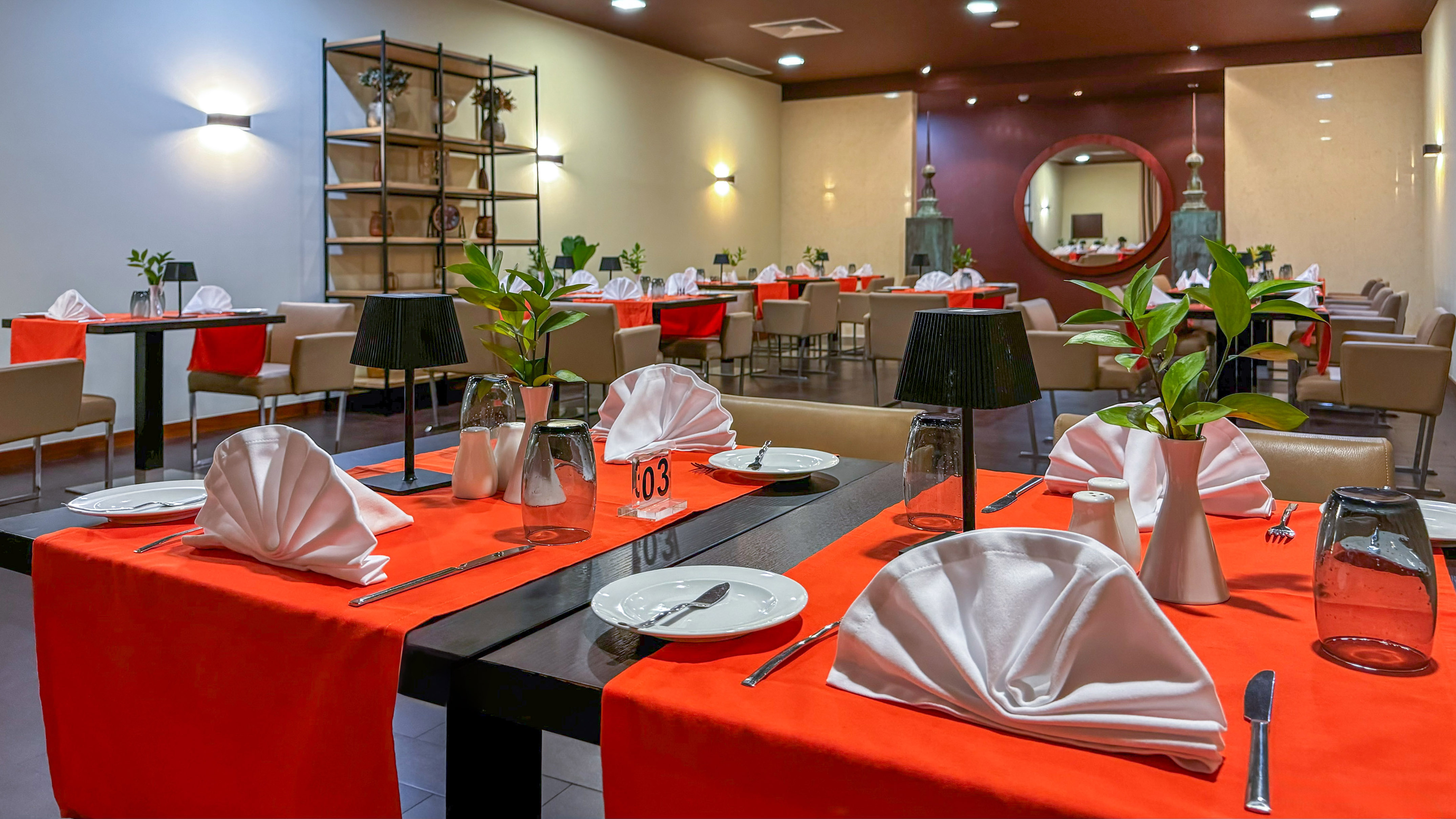Elegant restaurant dining room with red table settings and modern decor.