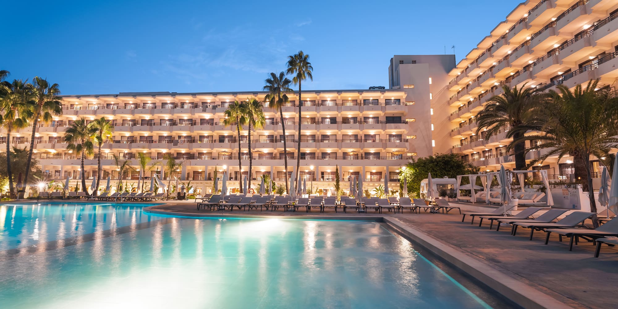 a pool with palm trees and a building with balconies