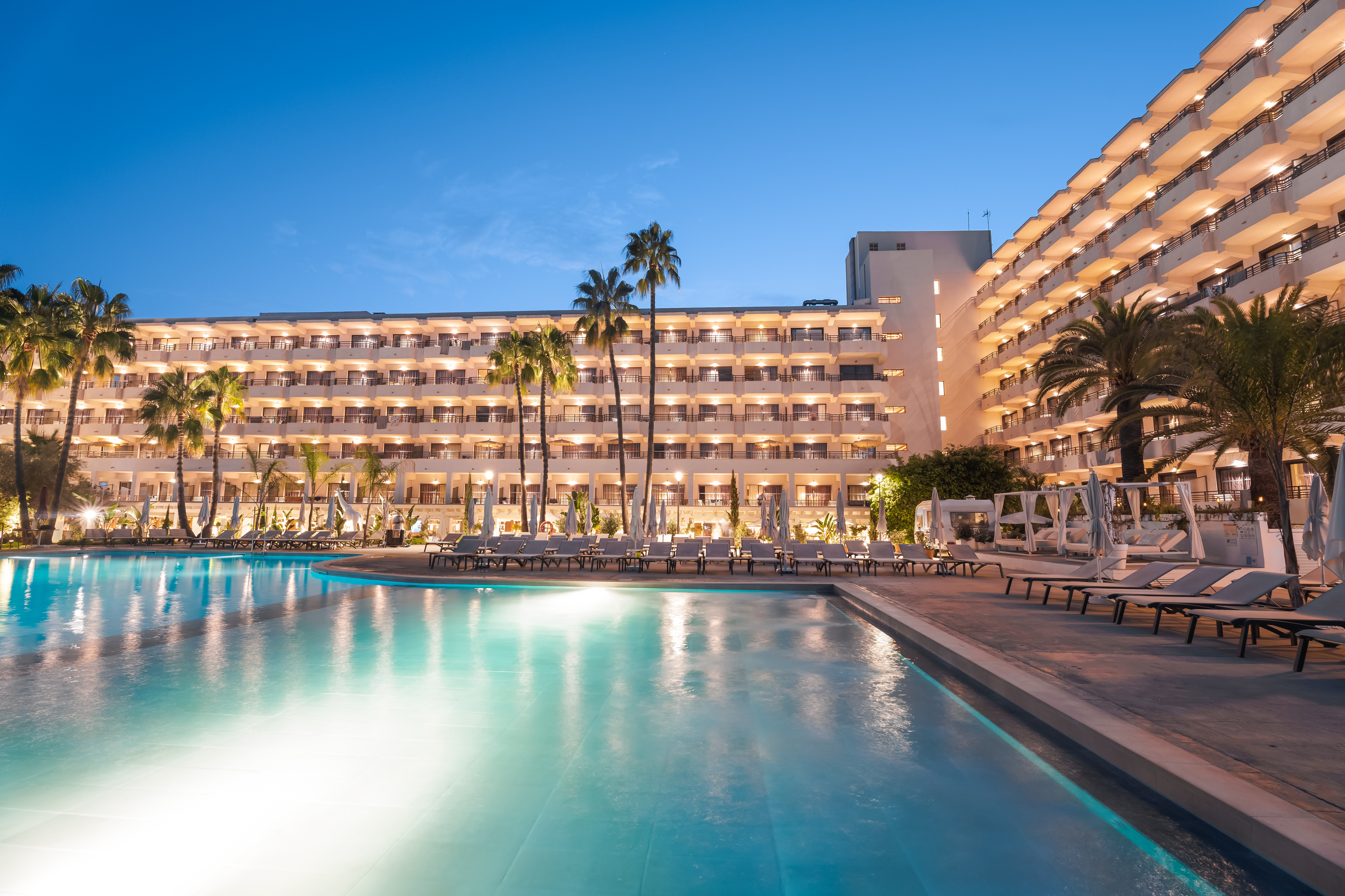 a pool with palm trees and a building with balconies