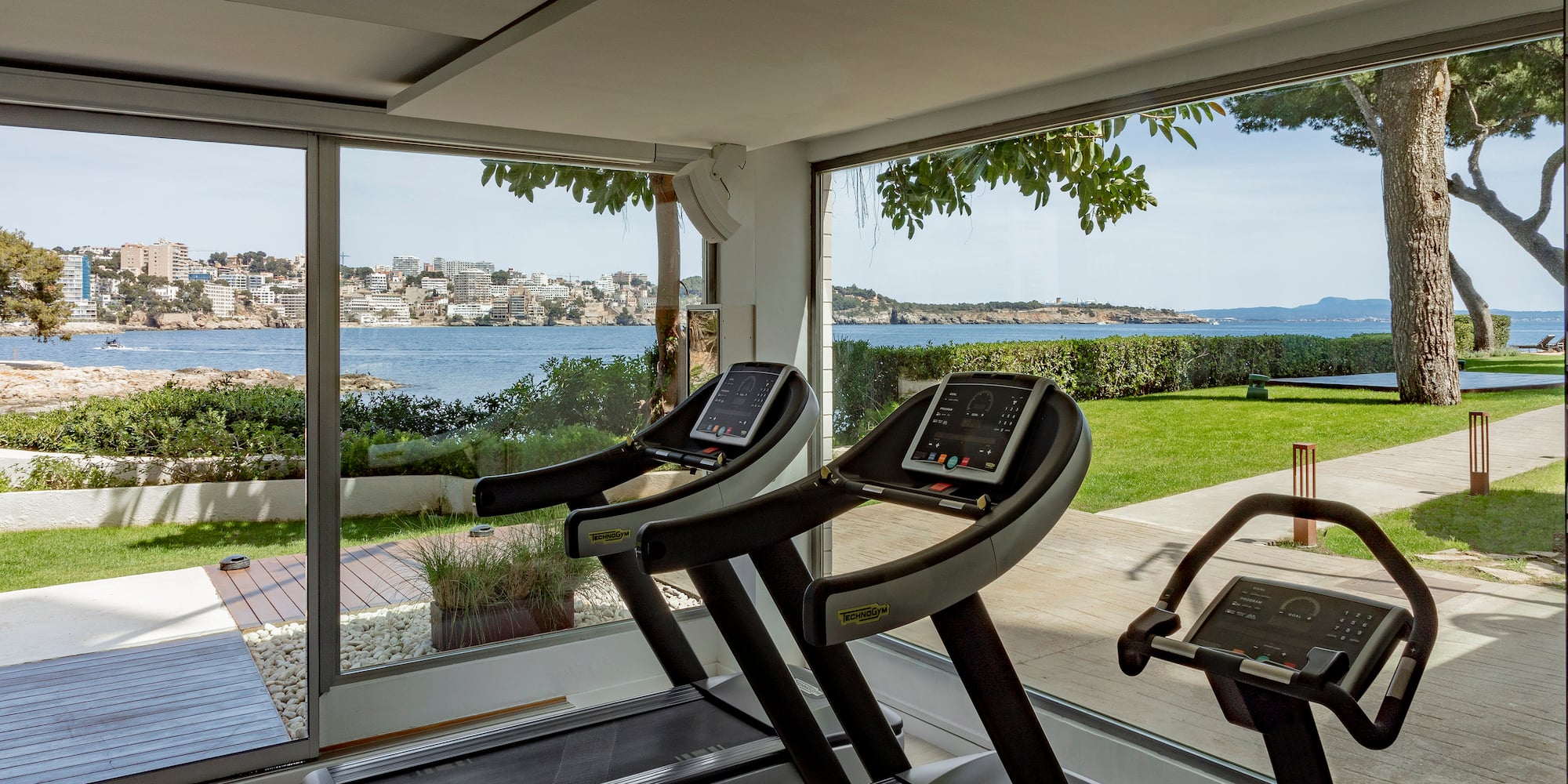 a gym with treadmills and a view of water and a city